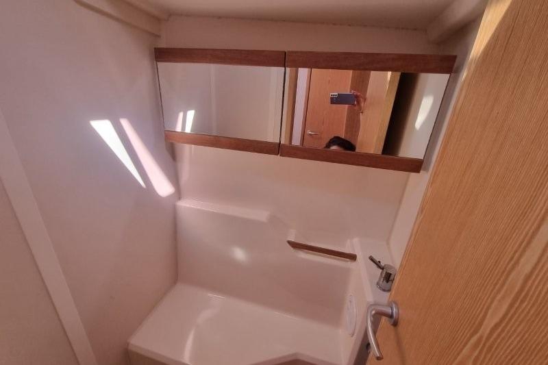 Compact bathroom interior of 2012 Hanse 445 yacht with mirror and sink.
