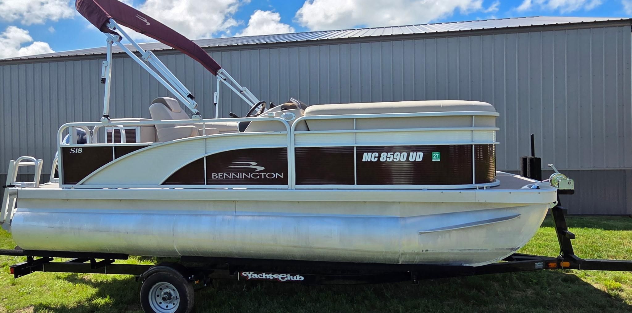 A 2018 Bennington 18SL pontoon boat on a trailer, parked in front of a building.