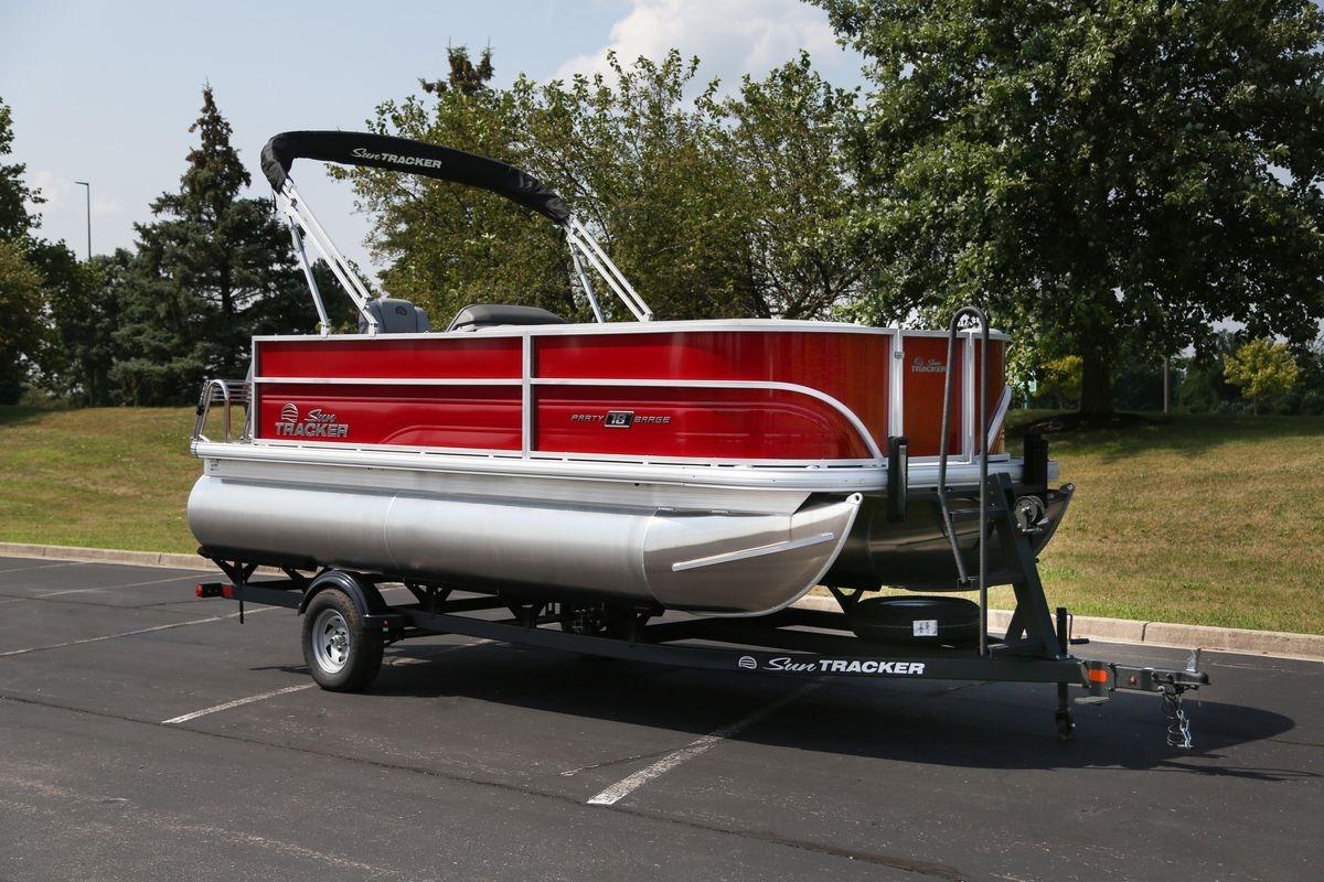 2026 Sun Tracker Party Barge 18 DLX pontoon boat on trailer in a parking lot.