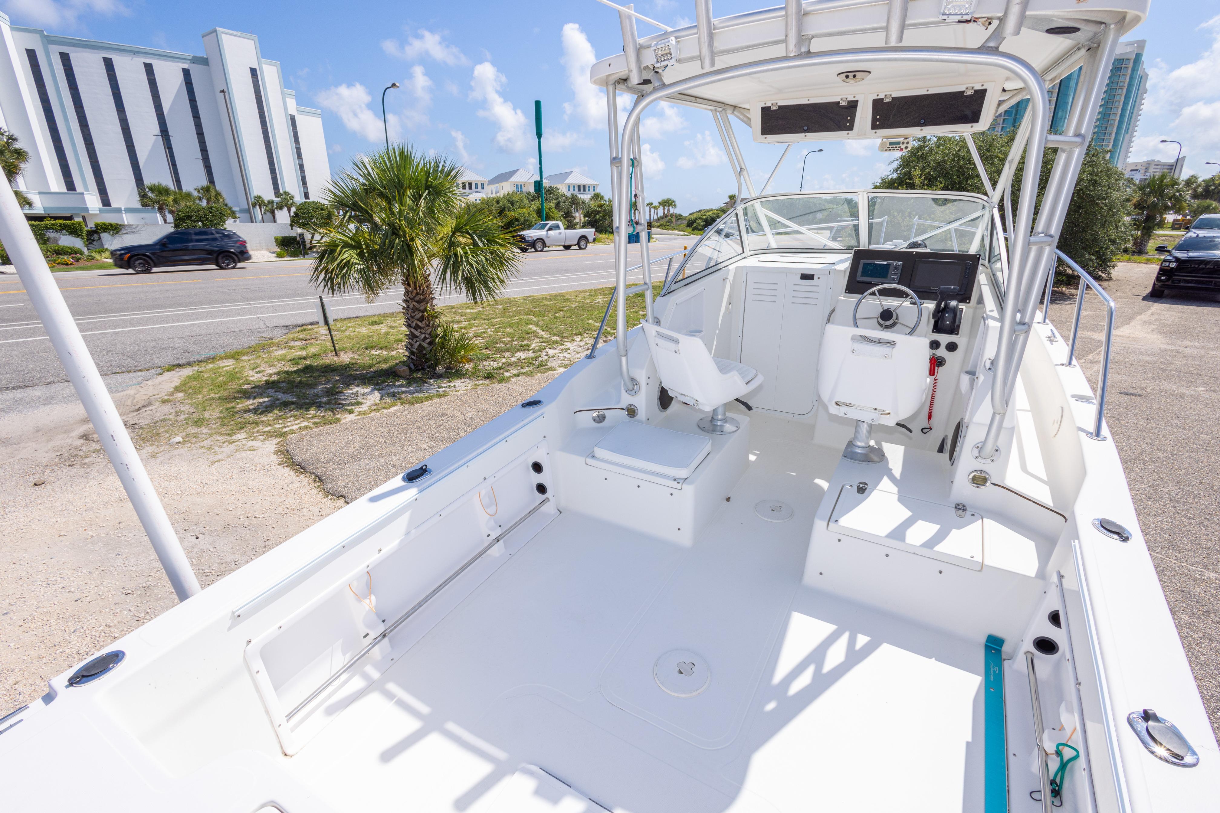 2007 Sea Boss 235 Walkaround boat with spacious deck and modern controls, parked near a road.