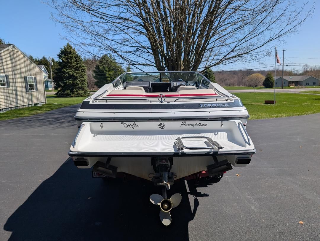 A white 1989 Formula F223LS boat is parked on a driveway.