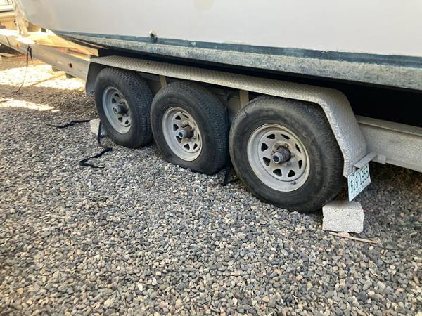 2006 Grady-White Bimini 306 boat trailer with triple axles on gravel.