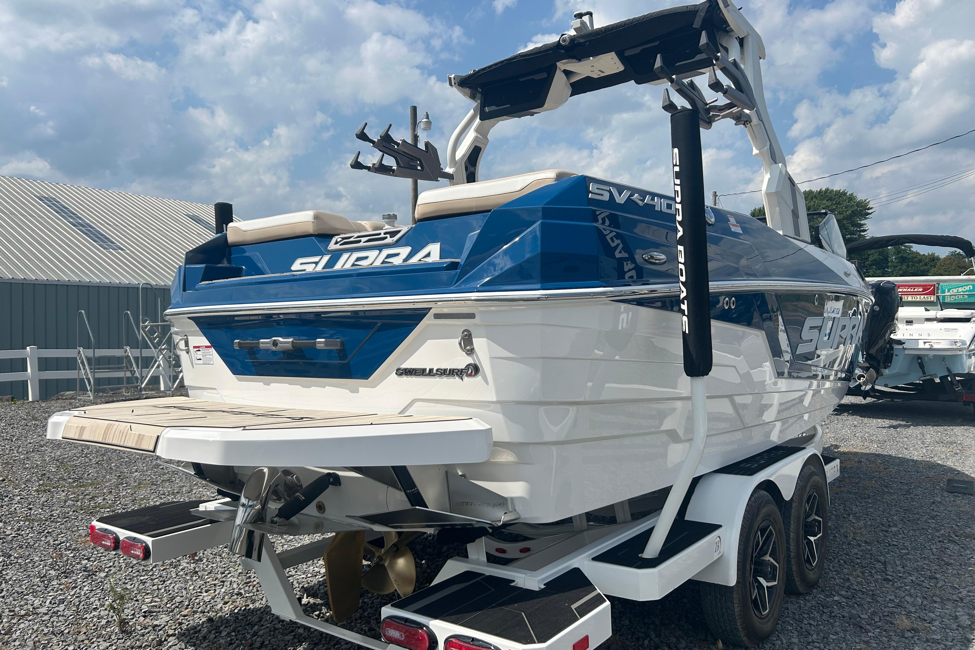 2025 Supra SV boat with blue and white design, parked on a trailer.