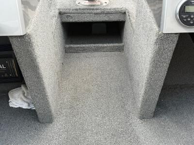 Gray carpeted interior of a boat with a storage compartment.