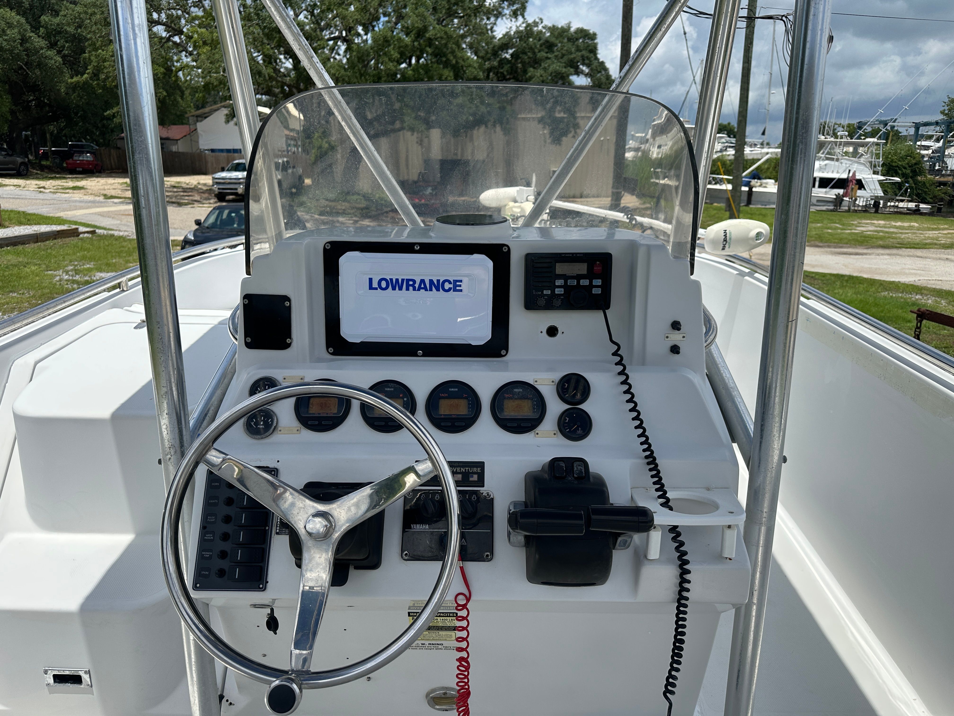 The image shows a boat's helm with a steering wheel and various instruments.