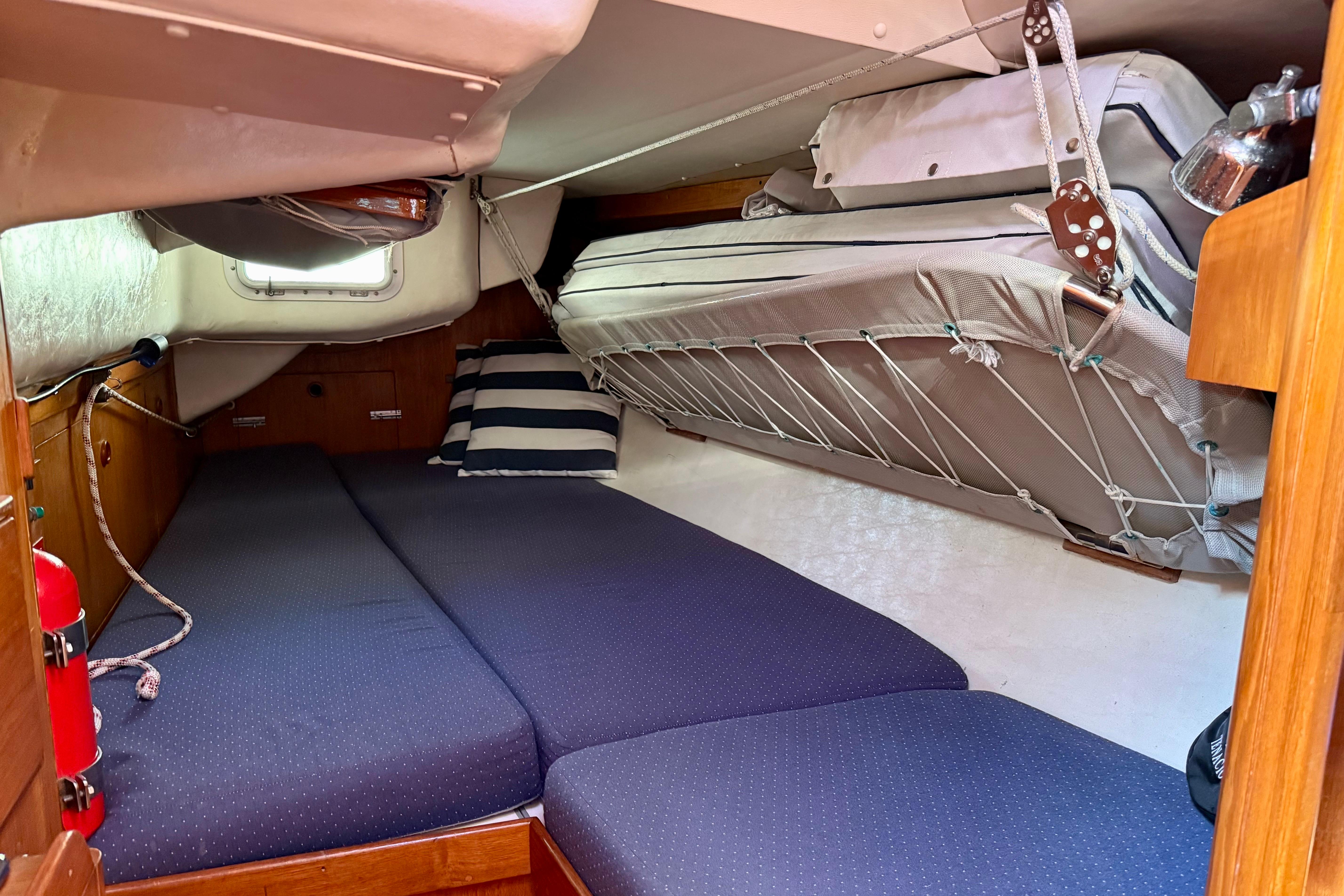 Cozy cabin interior of a 1991 J/Boats model with blue bedding and striped pillows.