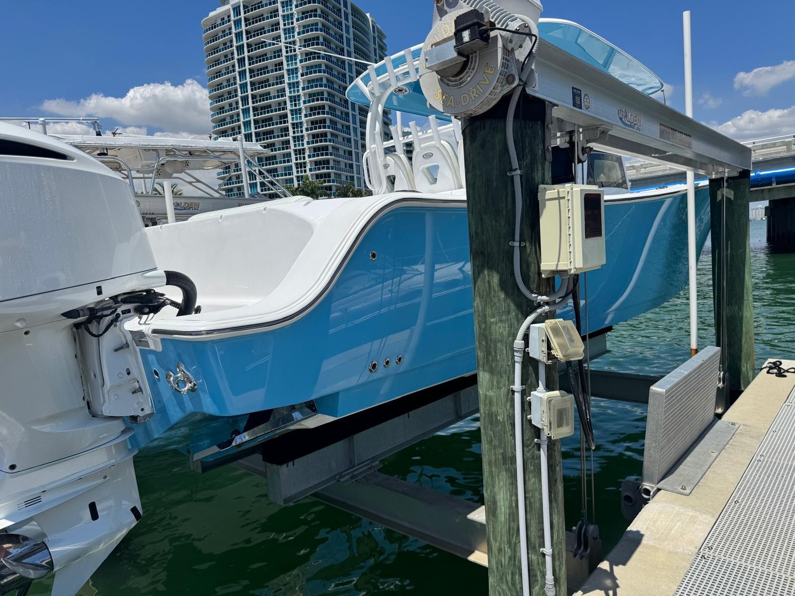 2020 Sportsman Open 352 Center Console boat on lift, docked near high-rise buildings.