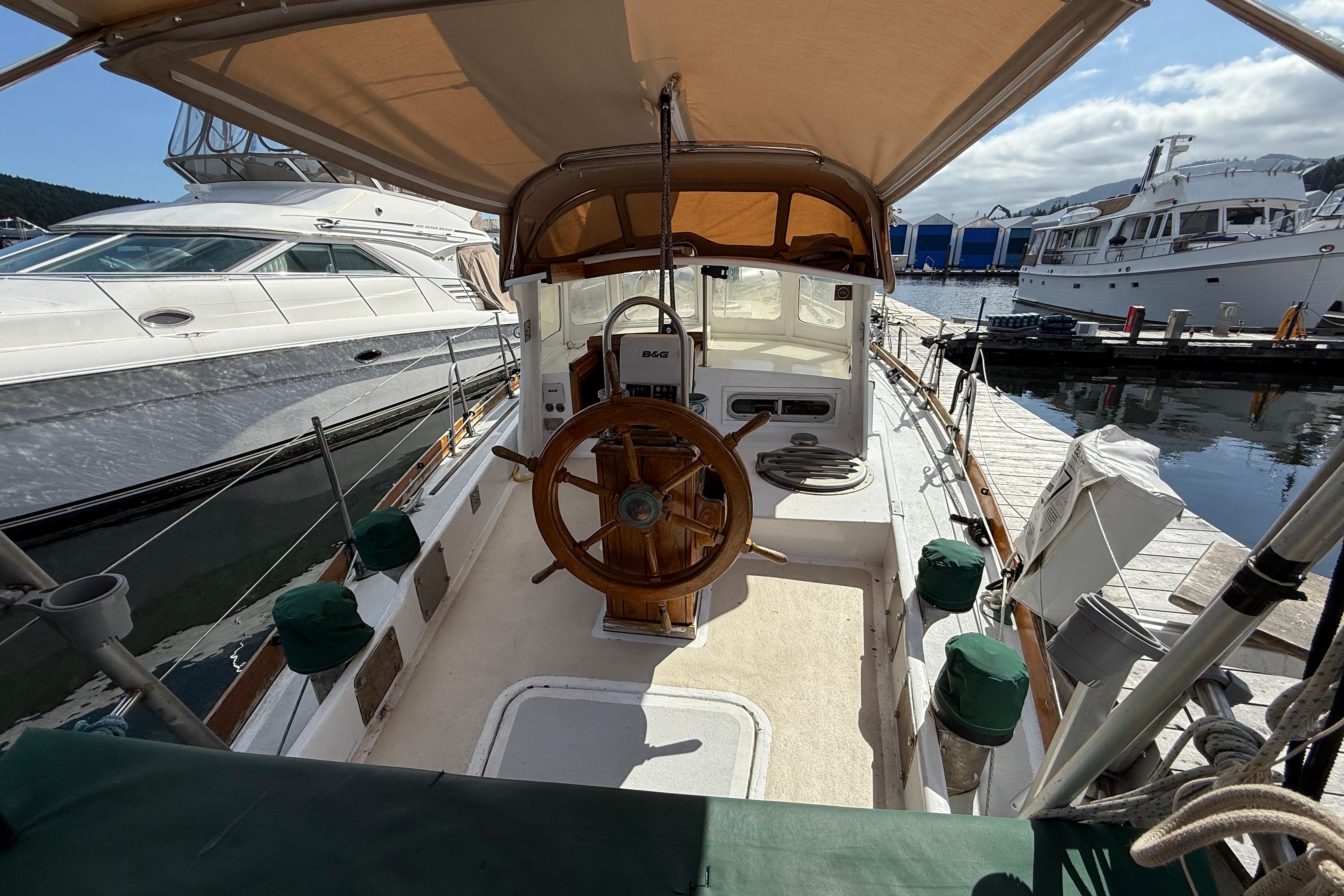 1974 Fraser 42 sailboat cockpit with wooden wheel, docked at marina.