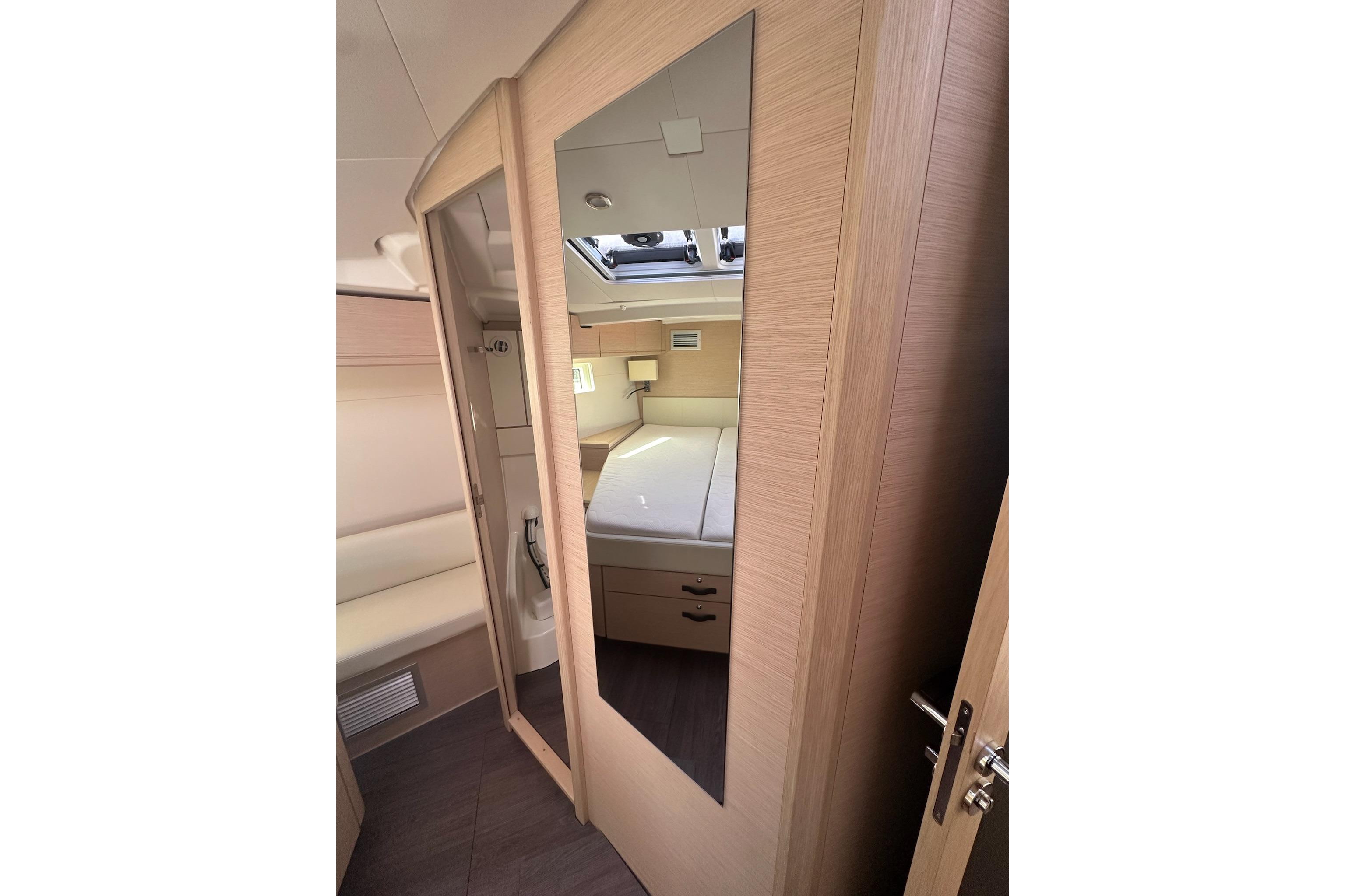 Interior of 2018 Jeanneau 51 yacht, featuring a mirrored wardrobe and cozy cabin space.