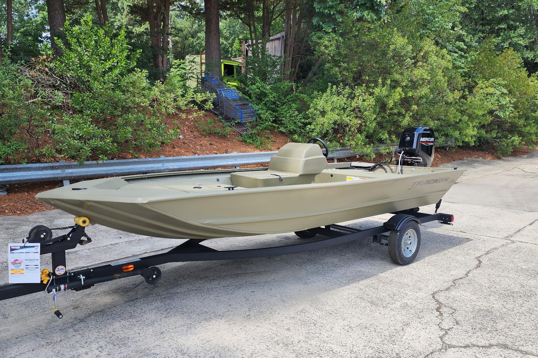 2026 Tracker Grizzly 1648 SC boat on trailer, parked outdoors near greenery.