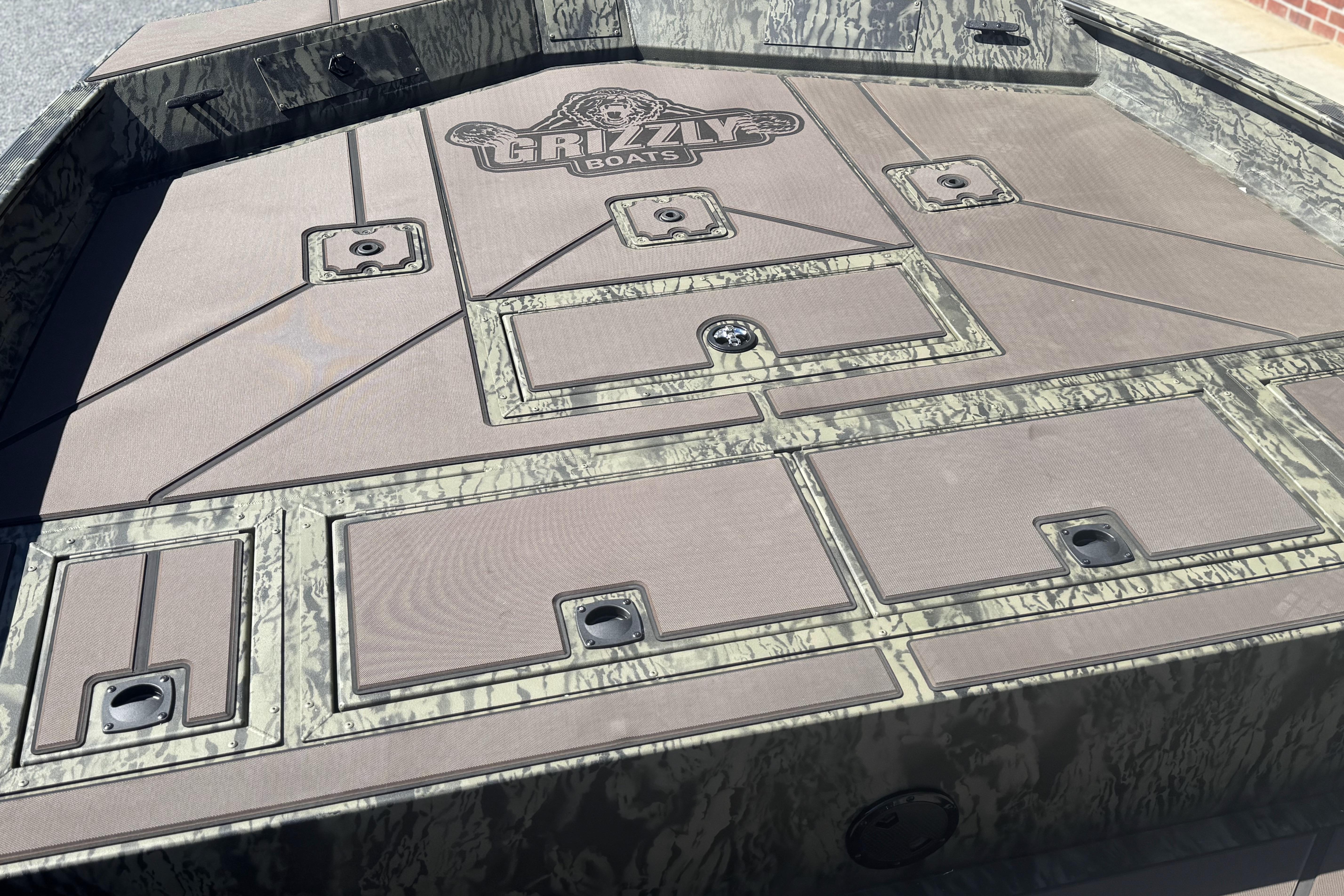 2026 Tracker Grizzly 2072 CC boat deck with storage compartments and camo design.