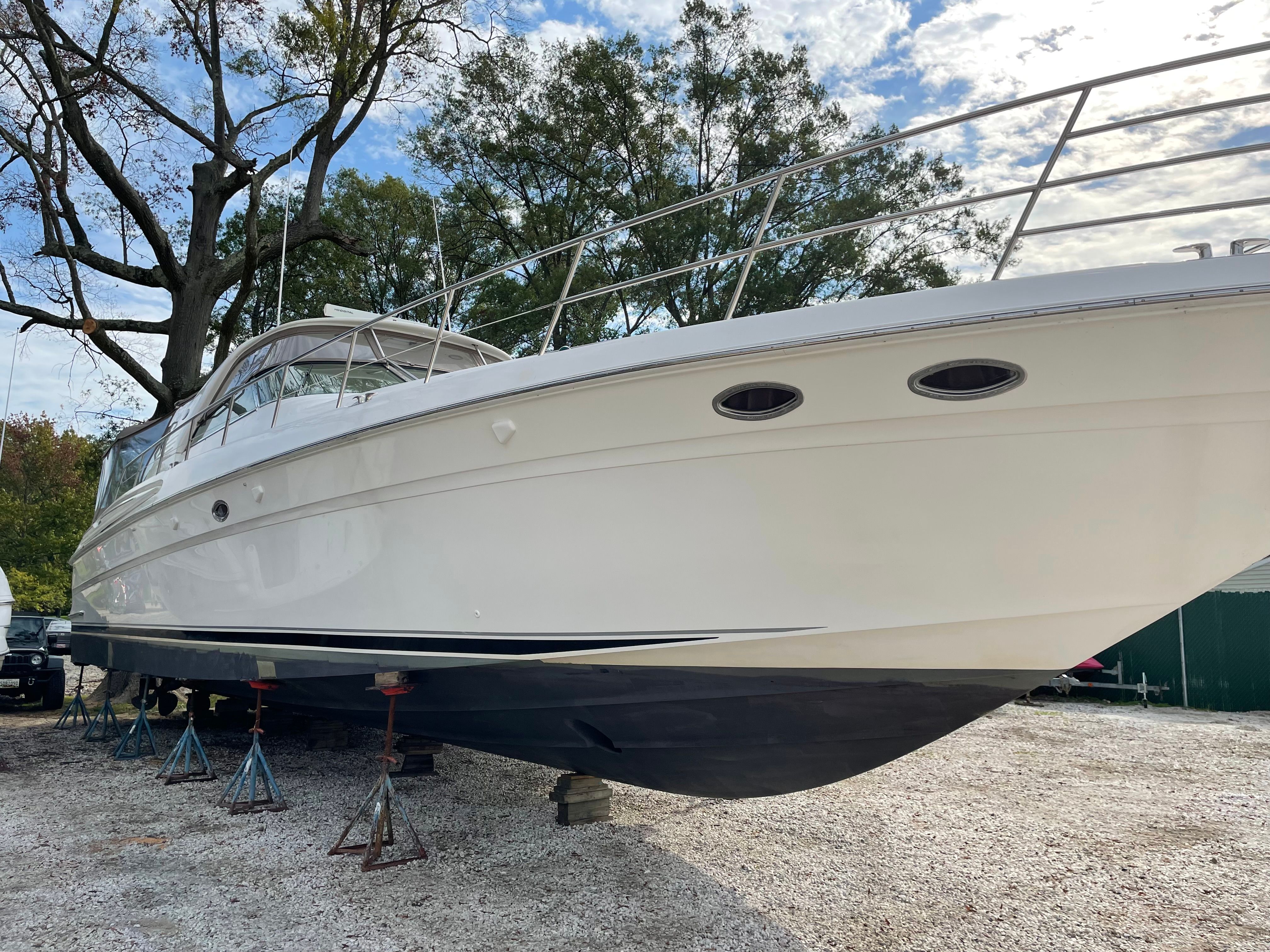 A 2003 Sea Ray S600 Sunsport is on a dry dock, surrounded by trees.