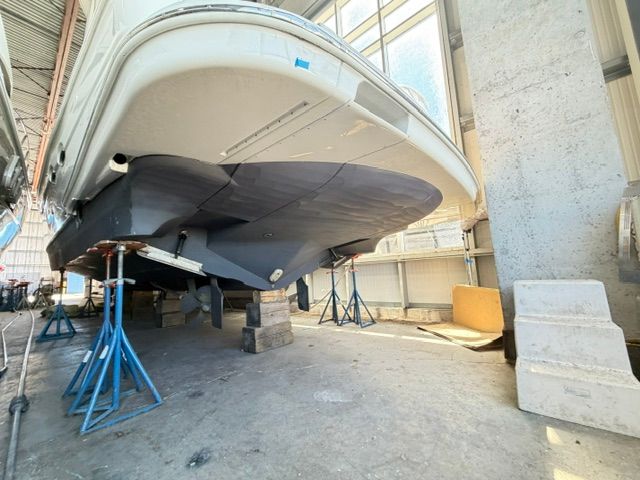 A 2005 Carver 44 Cockpit Motor Yacht is supported on stands in a warehouse.