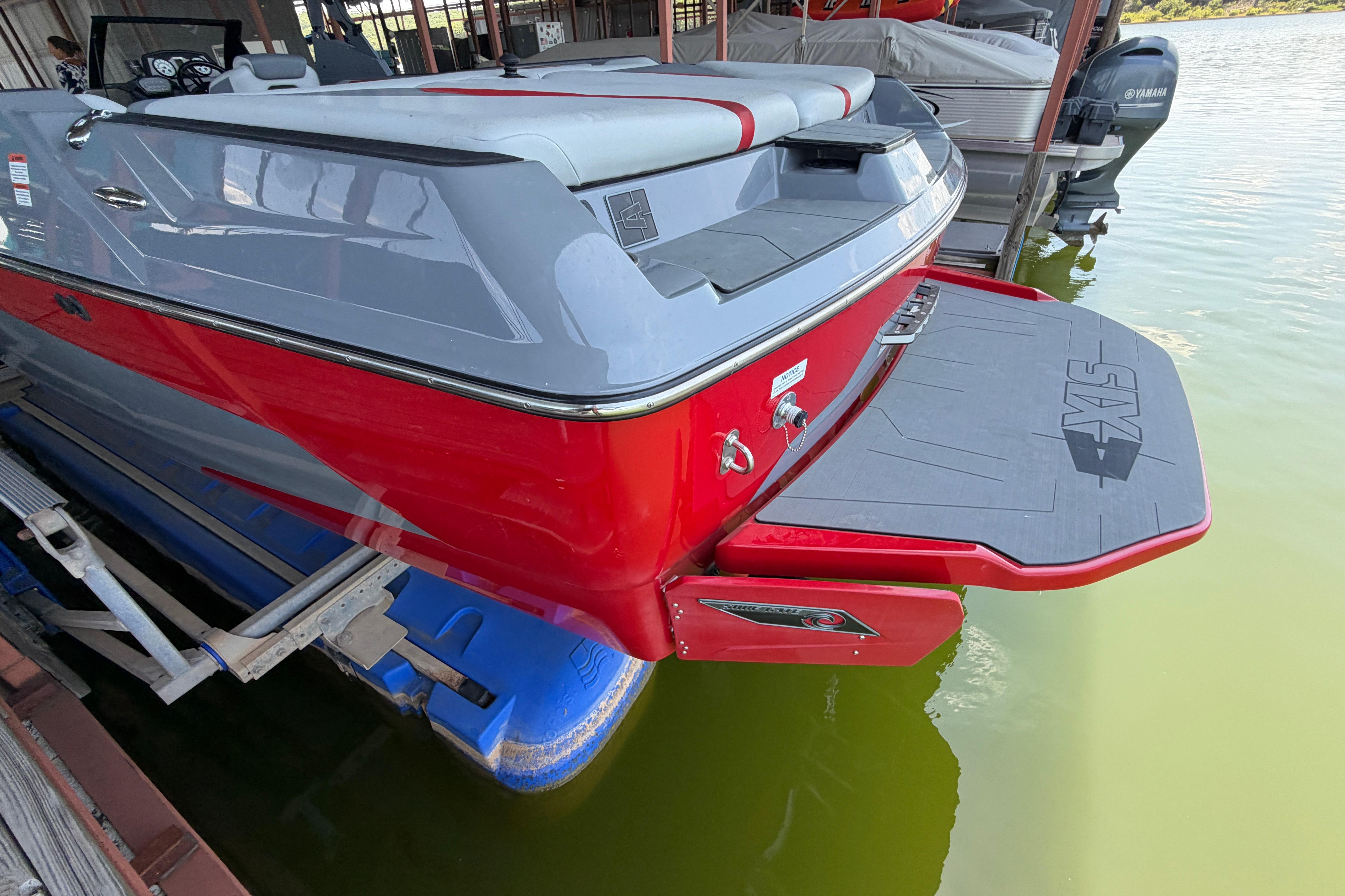 2021 Axis A24 boat with red and gray exterior, docked on calm water.