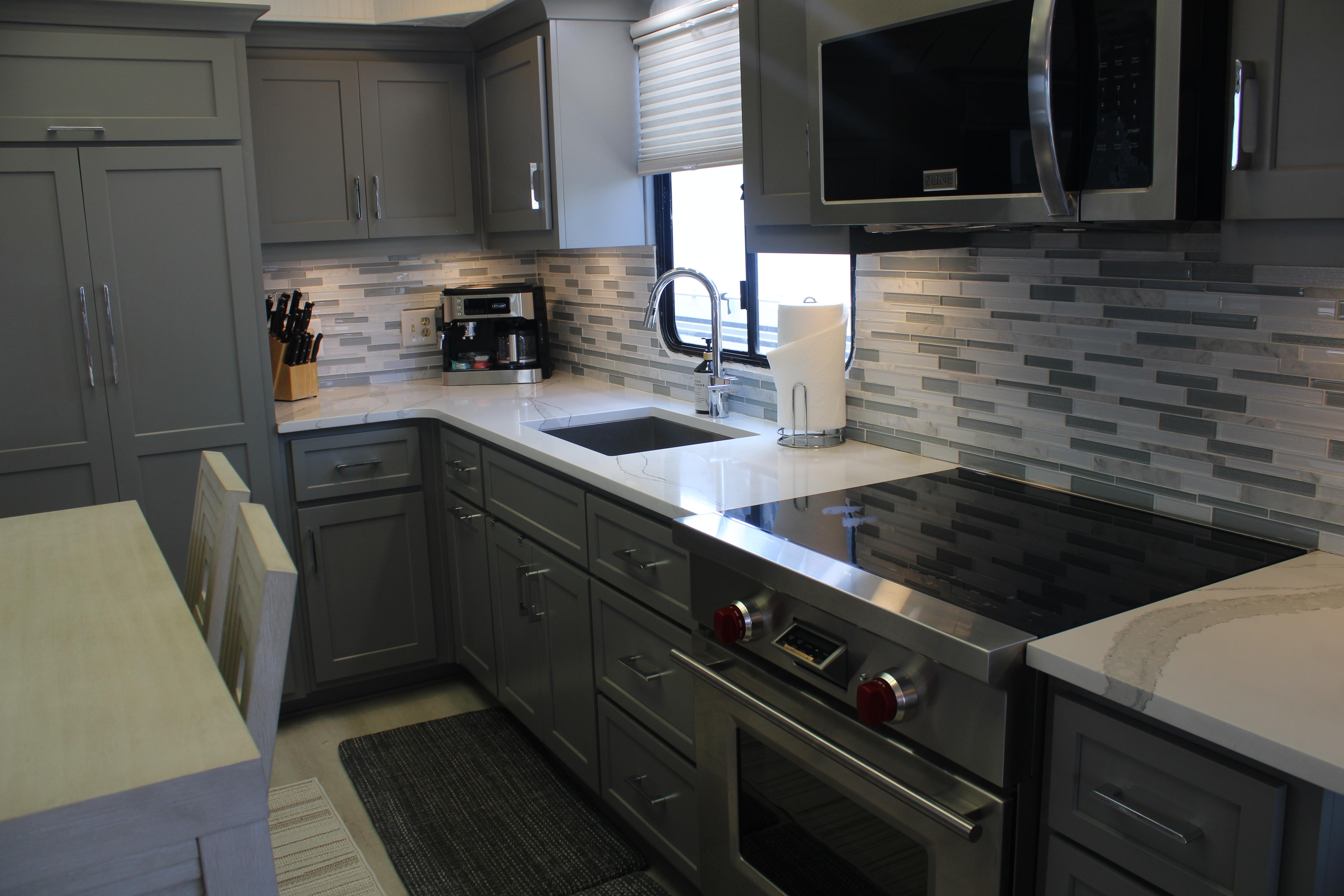 Modern kitchen in a 1992 Sumerset 66 houseboat with gray cabinets and stainless steel appliances.