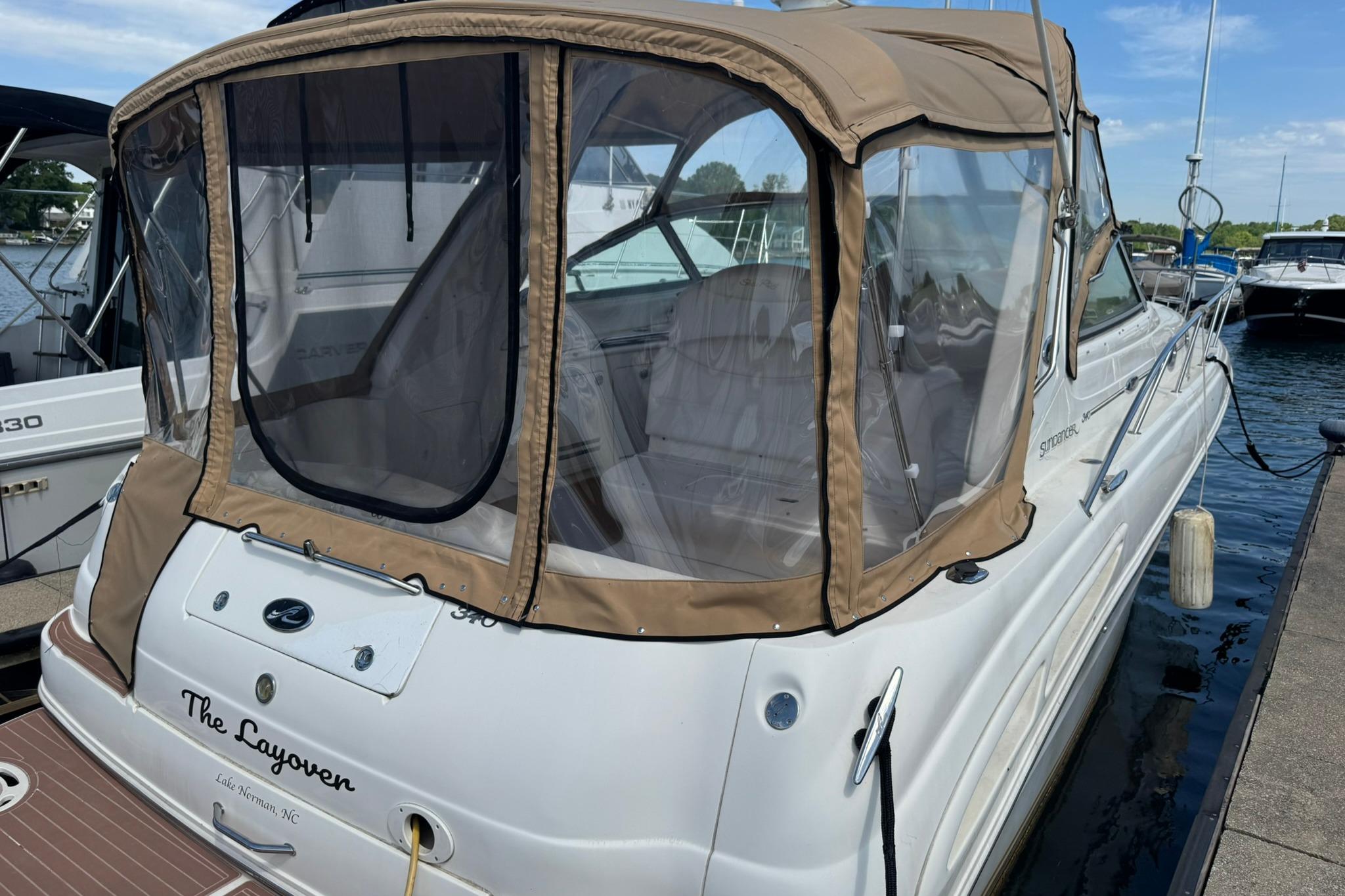 2001 Sea Ray 340 Sundancer docked with tan canopy and clear windows.