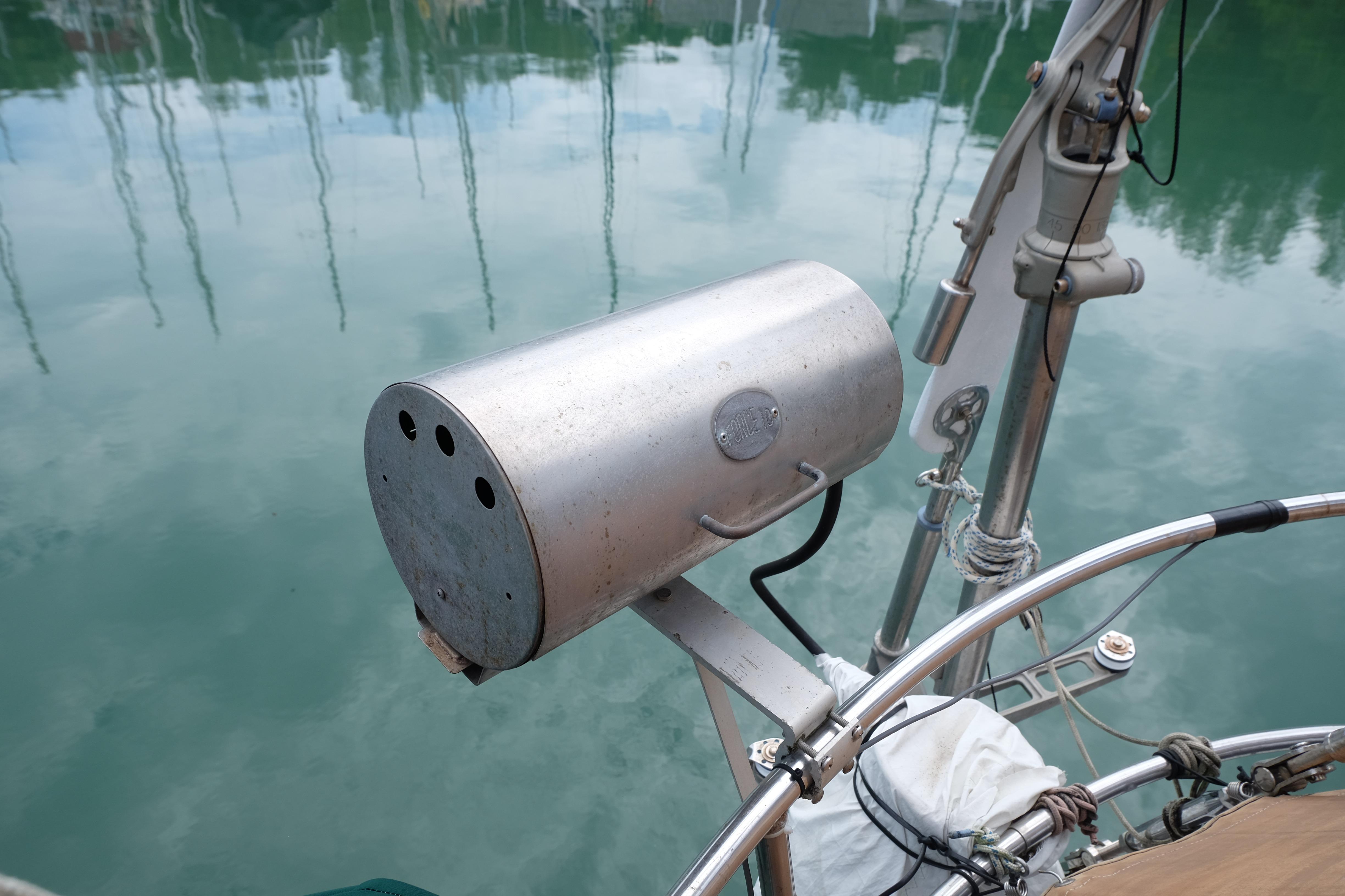 Stainless steel grill mounted on a 1979 Westwind 35 sailboat, reflecting on calm water.