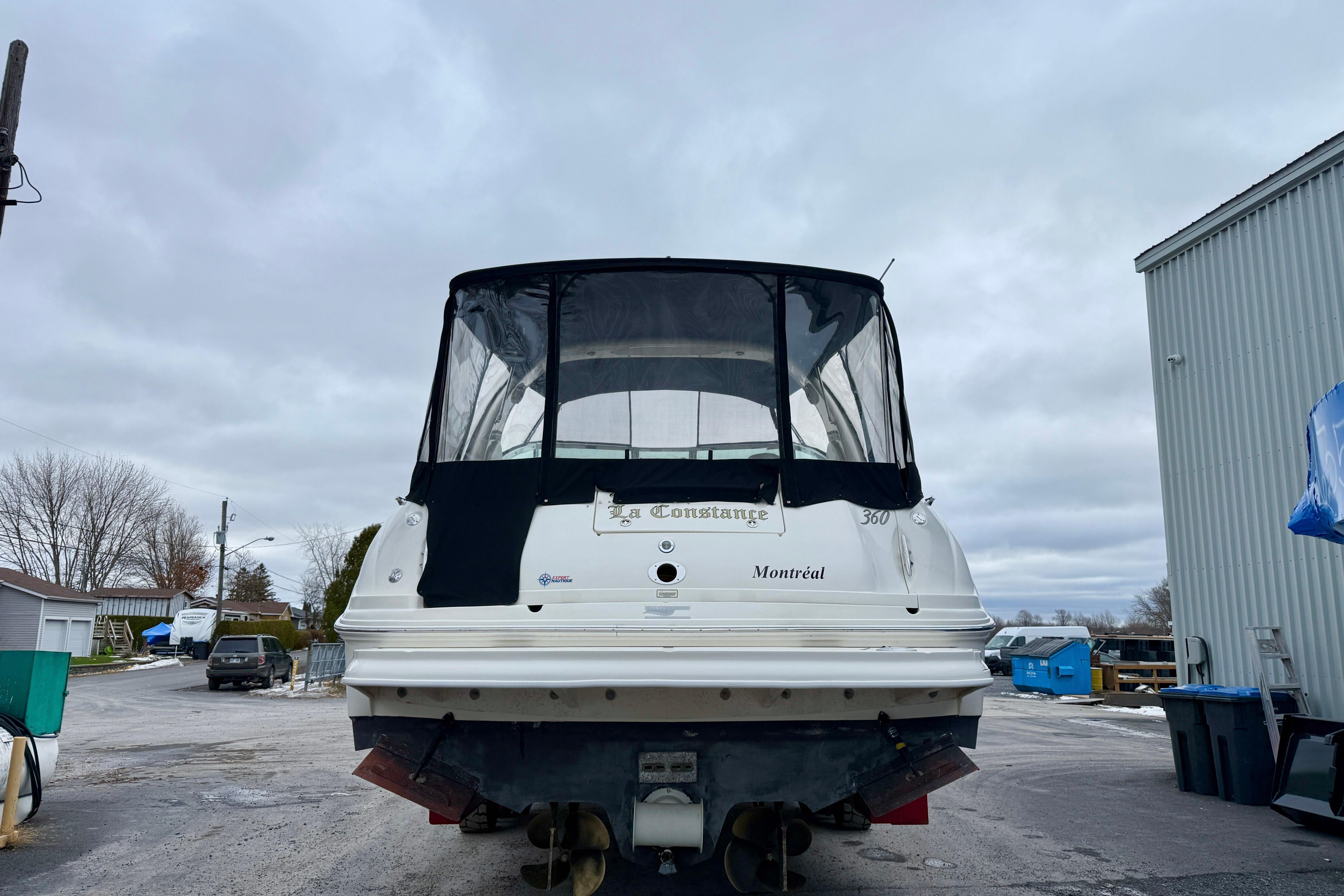 2004 Searay 360 Sundancer boat with black canopy, parked outdoors.