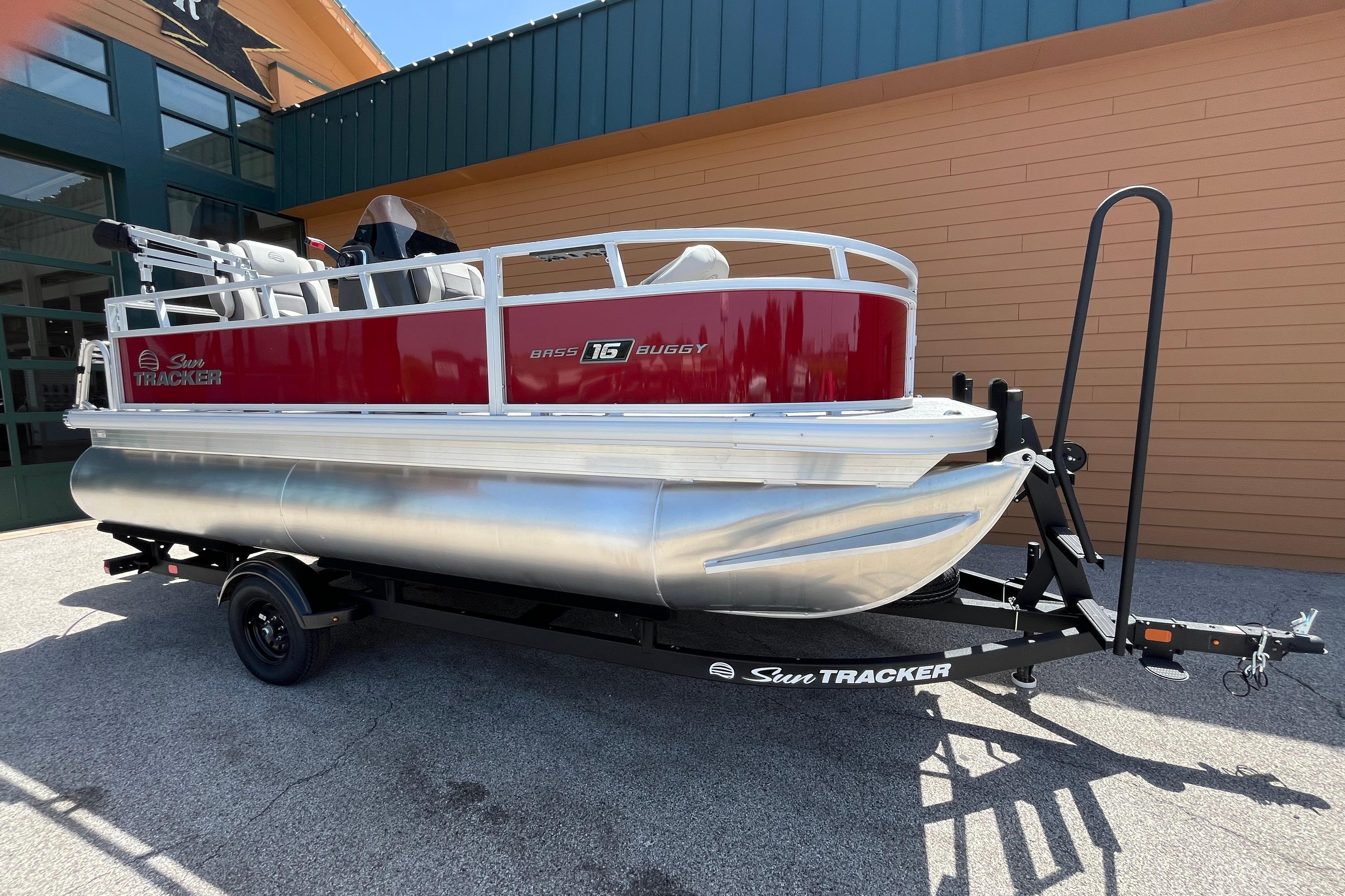 2026 Sun Tracker Bass Buggy 16 XL Select pontoon boat on trailer, parked outdoors.