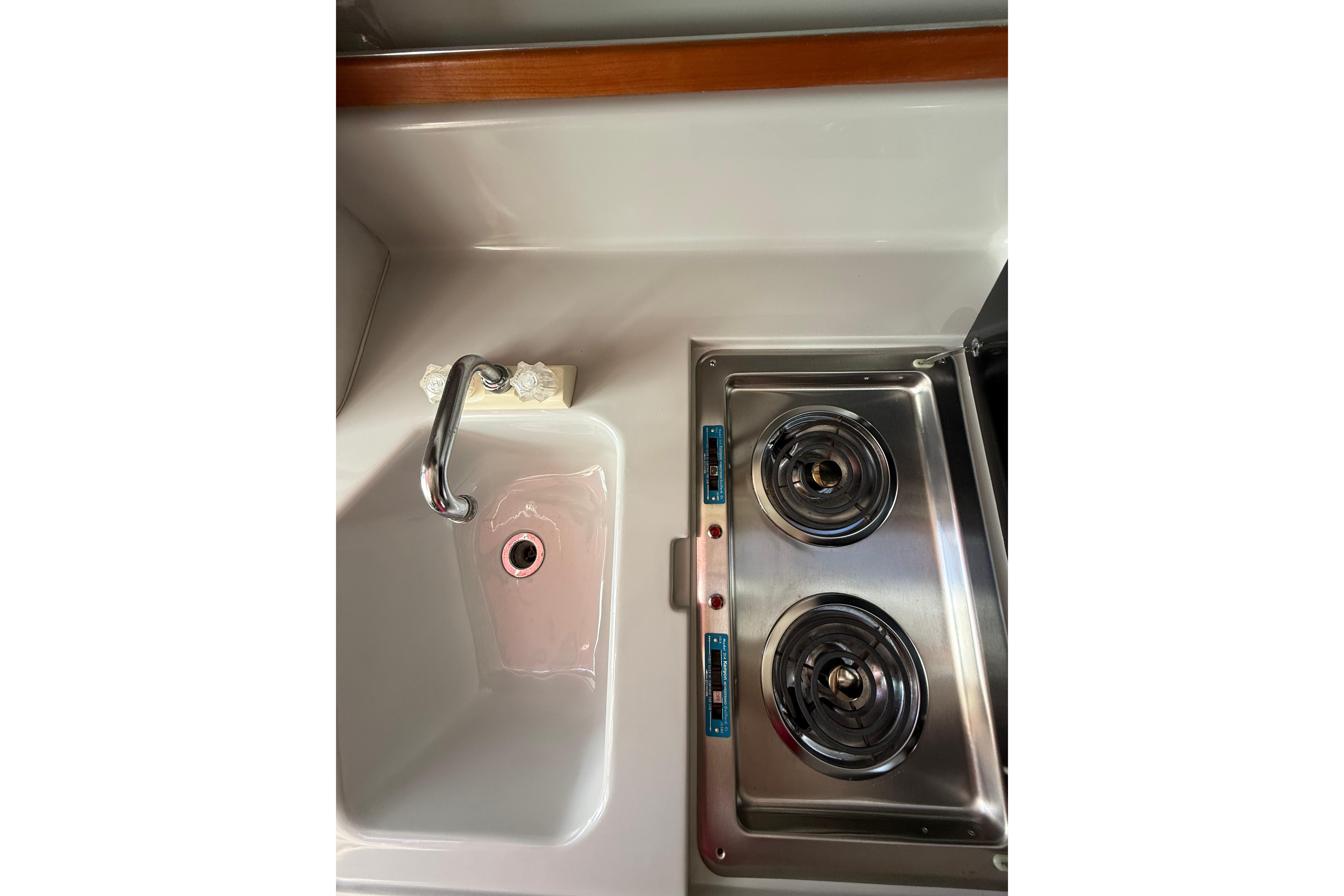 1990 Sea Ray 310 Express Cruiser kitchen with sink and dual-burner stove.
