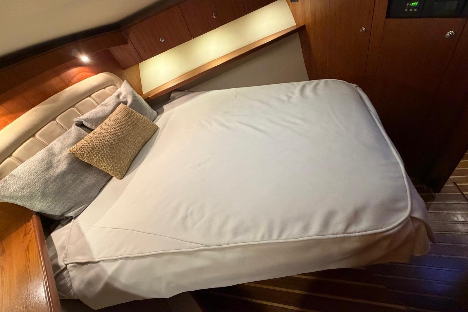 Luxurious cabin interior of 2007 Tiara Yachts 3900 Convertible with cozy bed and wooden accents.