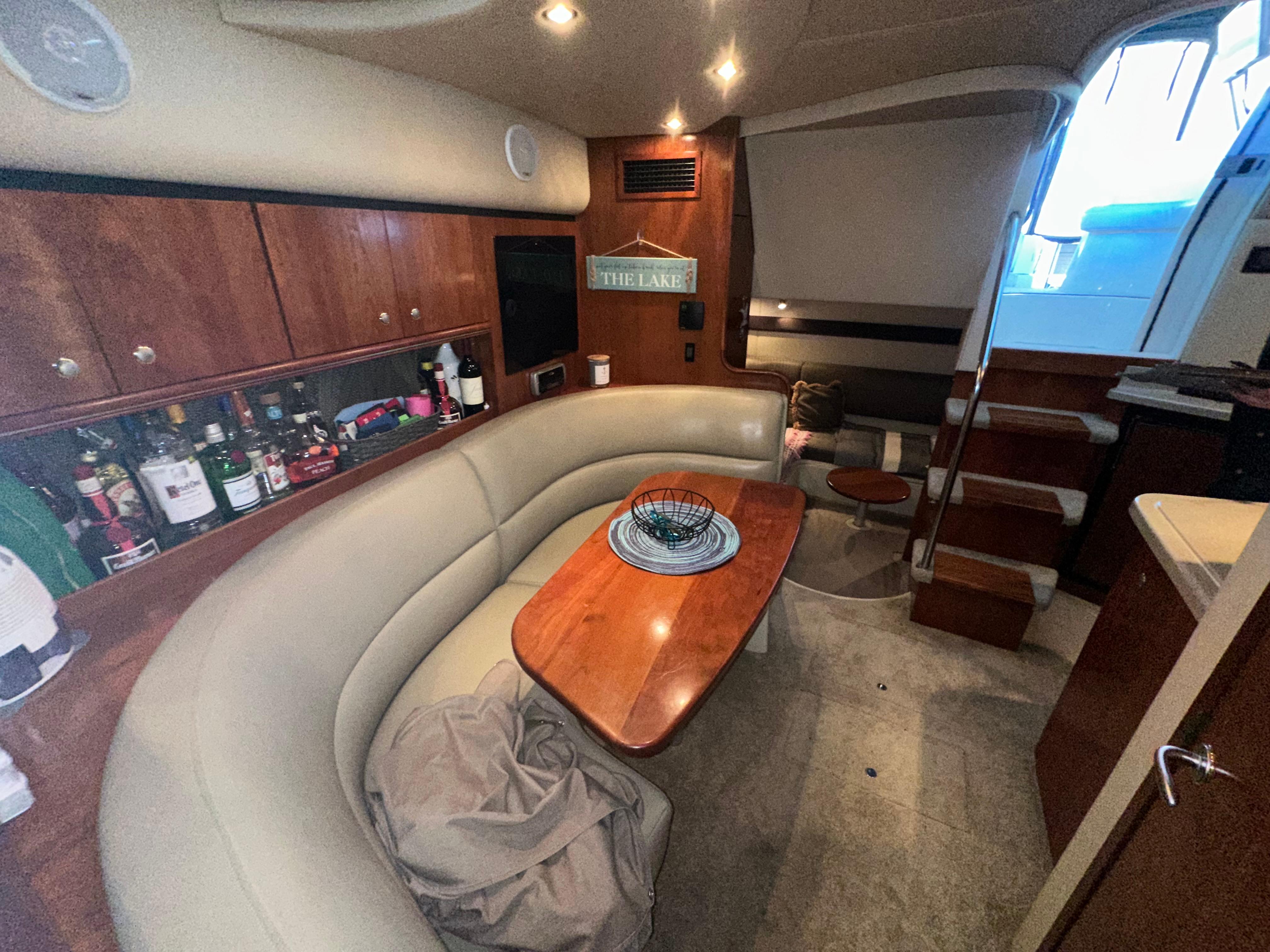 2005 Cruisers Yachts 340 Express interior with curved seating and wooden table.