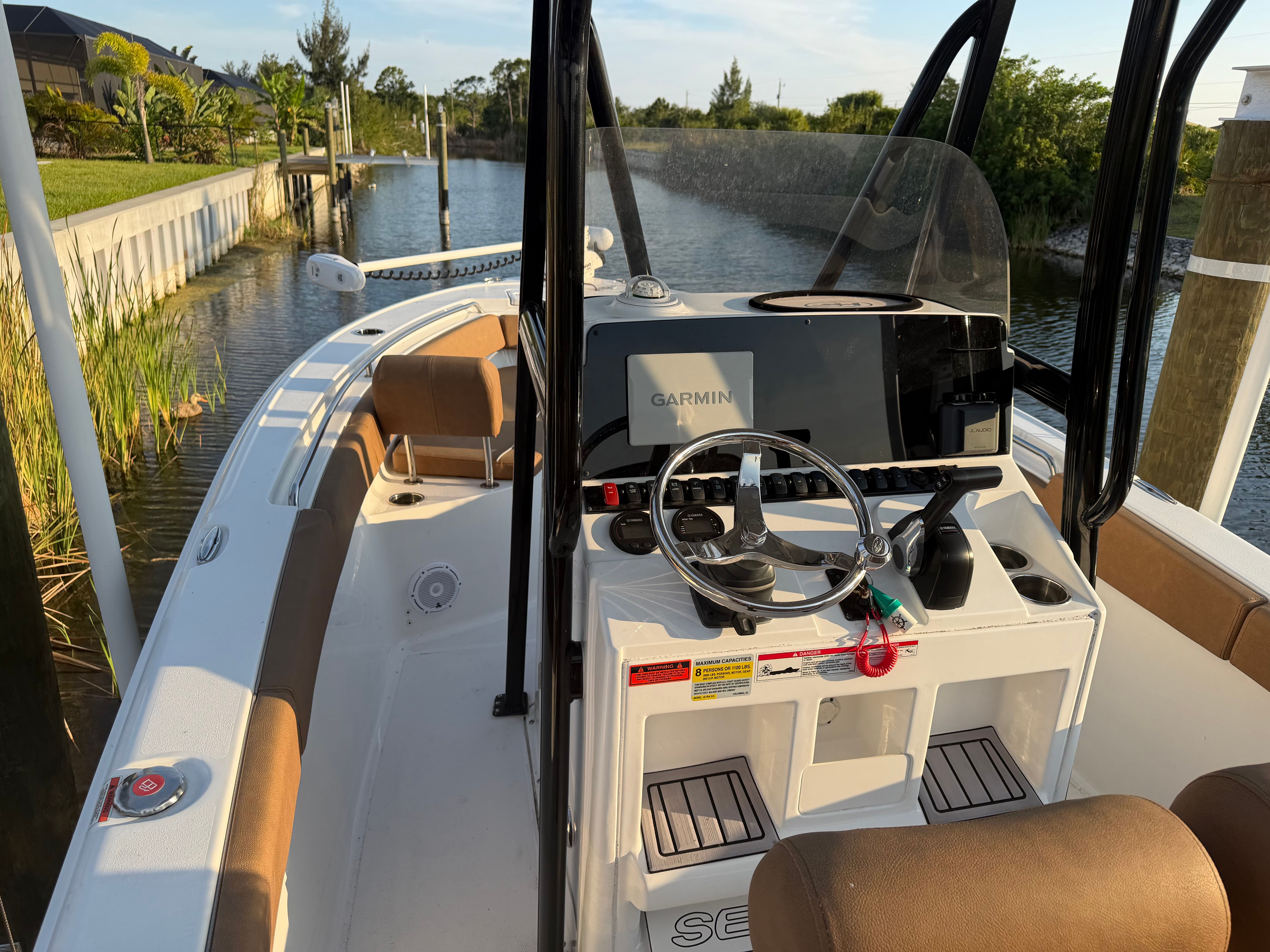 The image shows a 2024 Sea Hunt Ultra 219 boat docked in a calm canal.