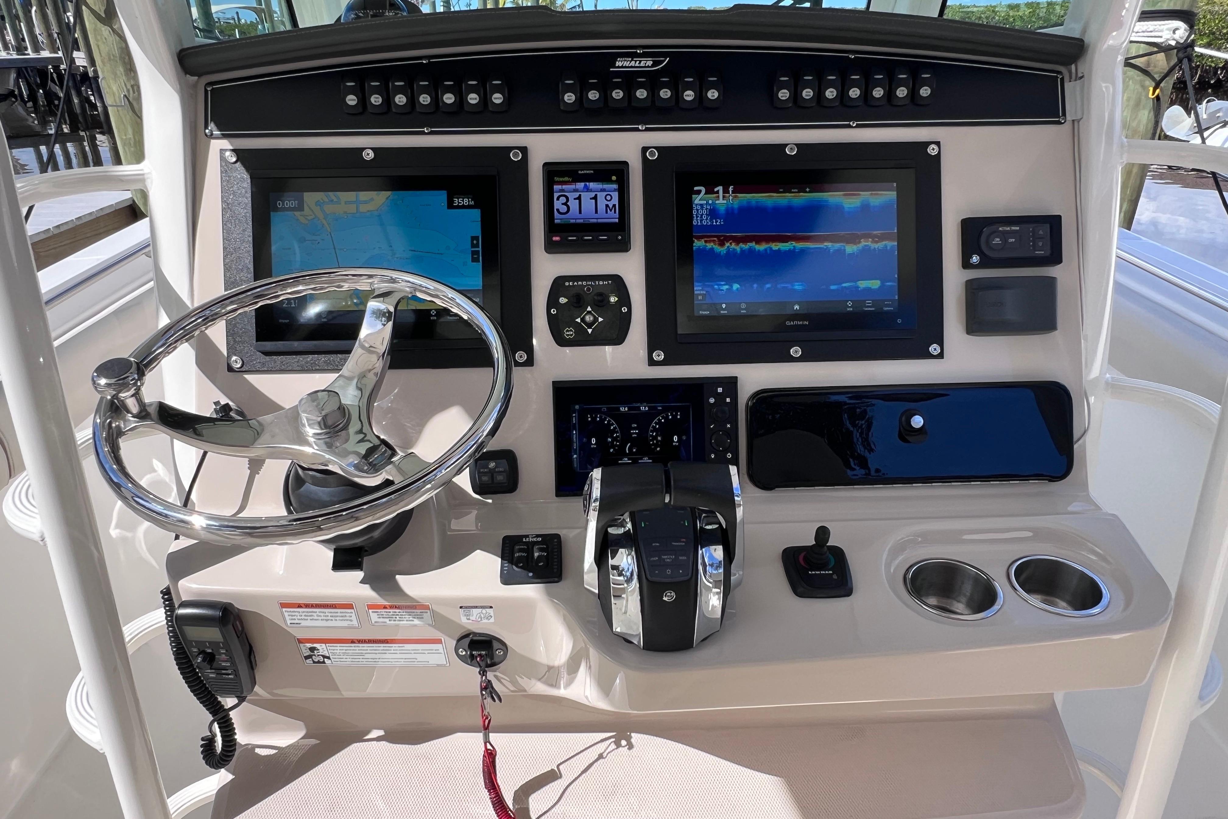 Control panel of 2021 Boston Whaler 330 Outrage with navigation screens and steering wheel.