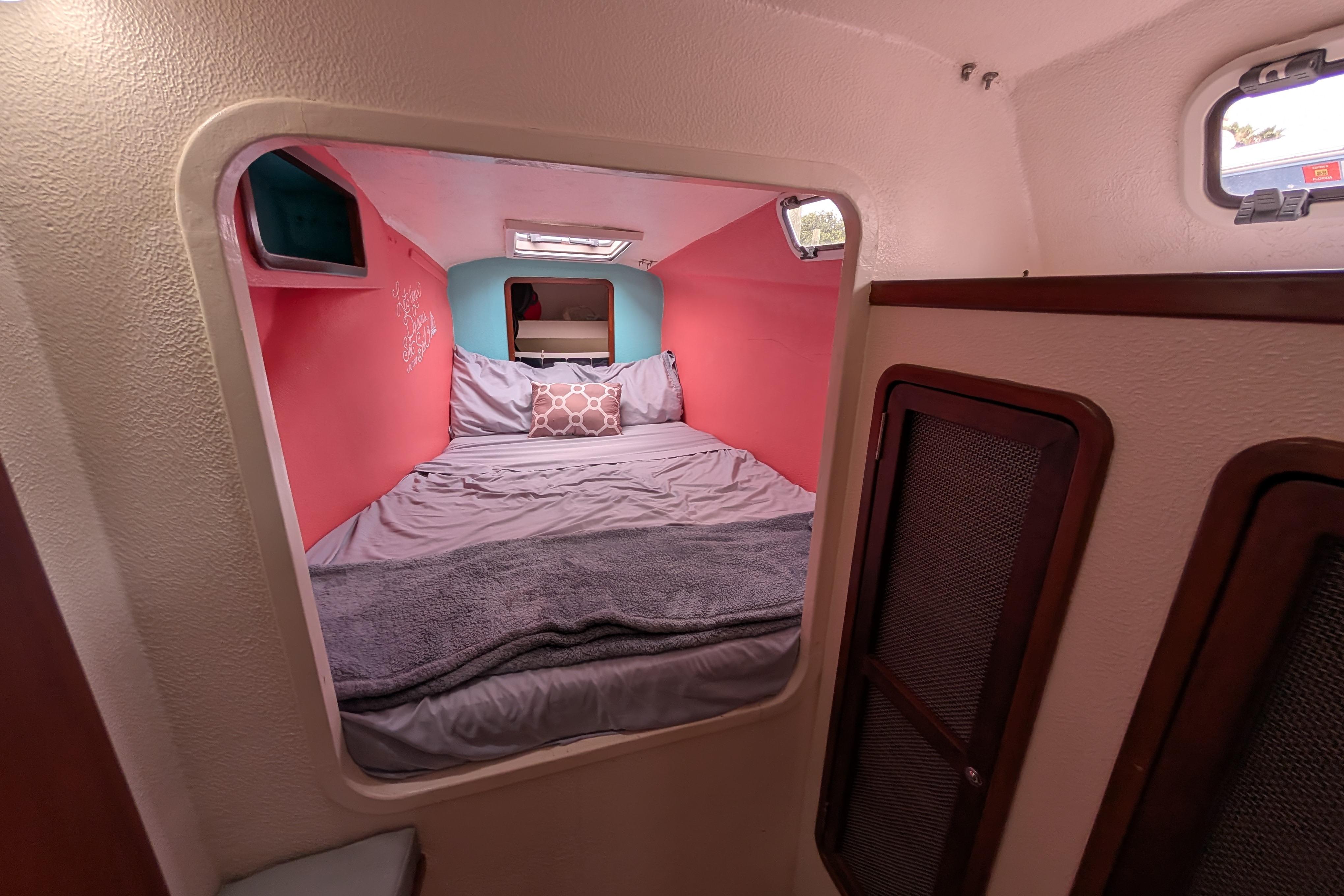Cozy cabin interior of 1999 Island Spirit 37 sailboat with colorful bedding and storage.