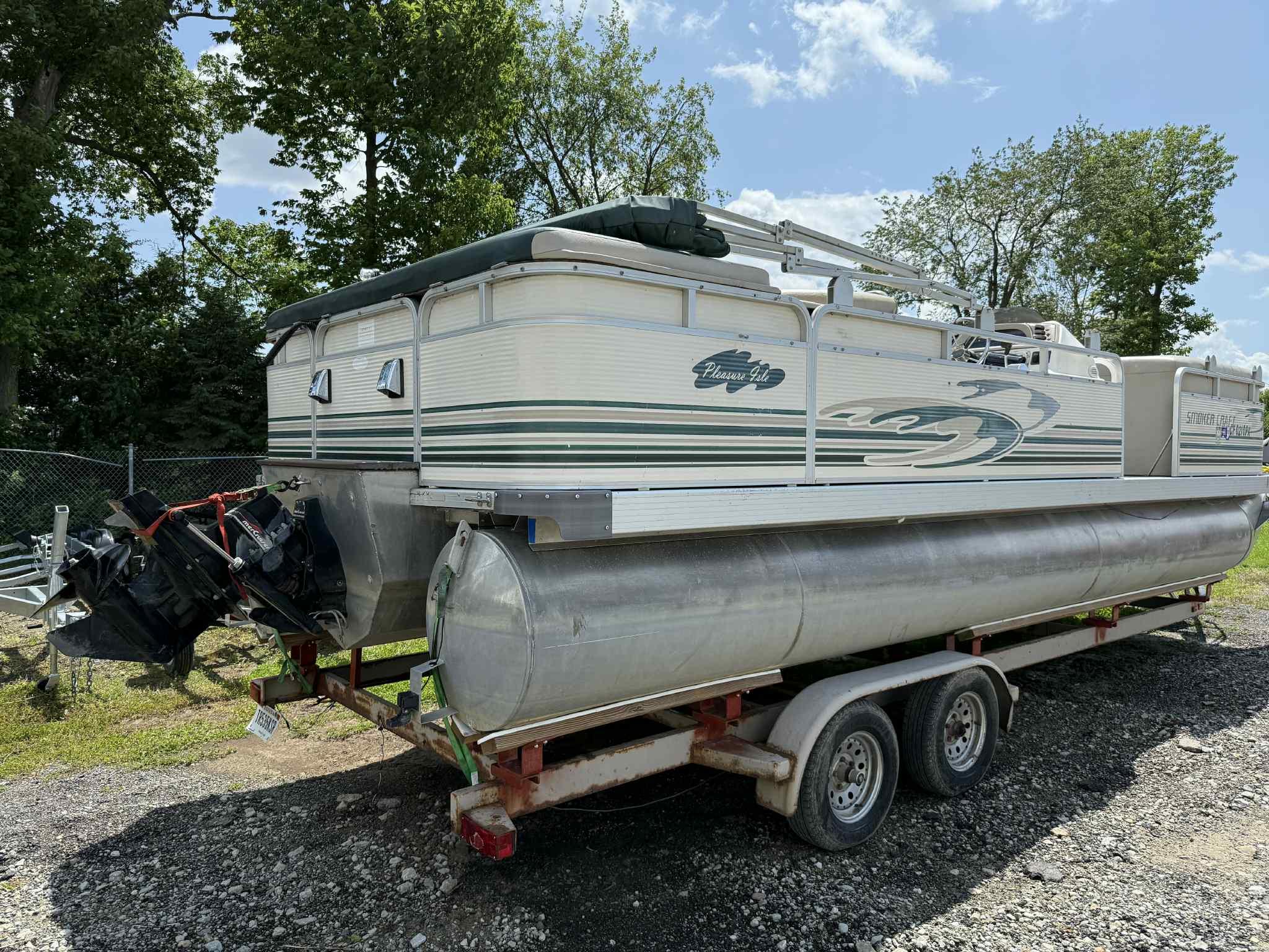 1999 Smoker Craft 8526 Pleasure Isle I/O pontoon boat on trailer, parked outdoors.