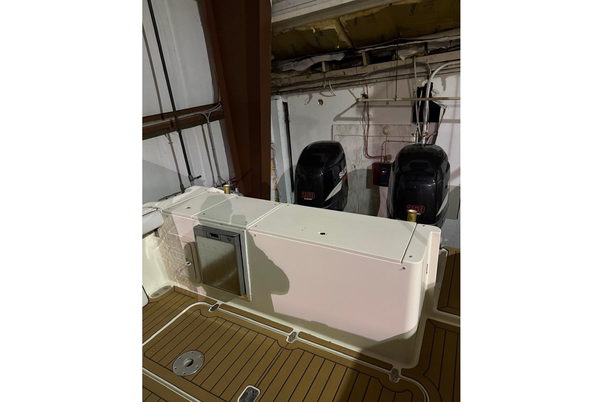 2000 Pursuit 3070 Offshore Center Console with dual Suzuki outboard engines in storage.