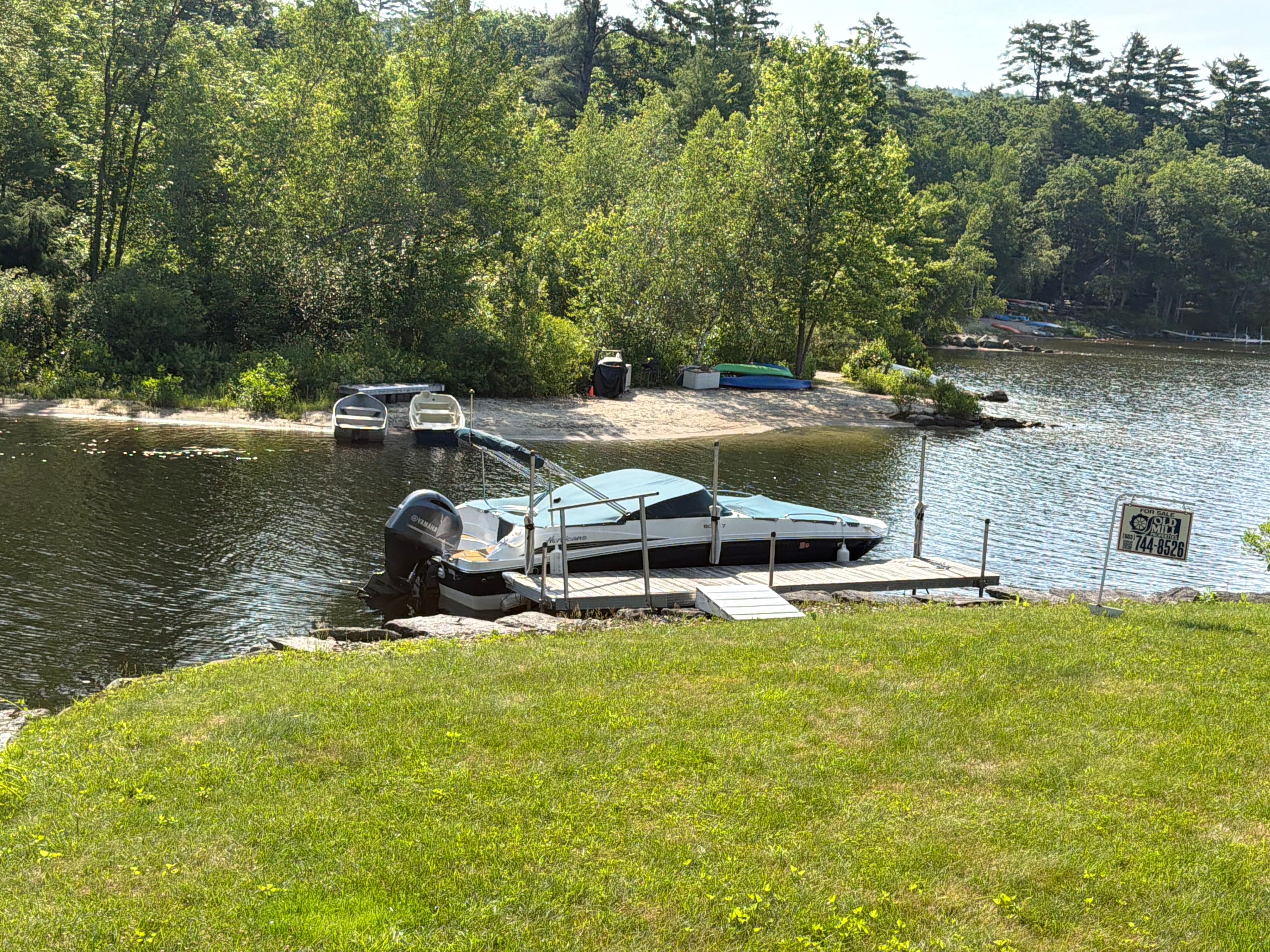 A 2022 Hurricane SunDeck 217 OB docked at a tranquil lakeside.