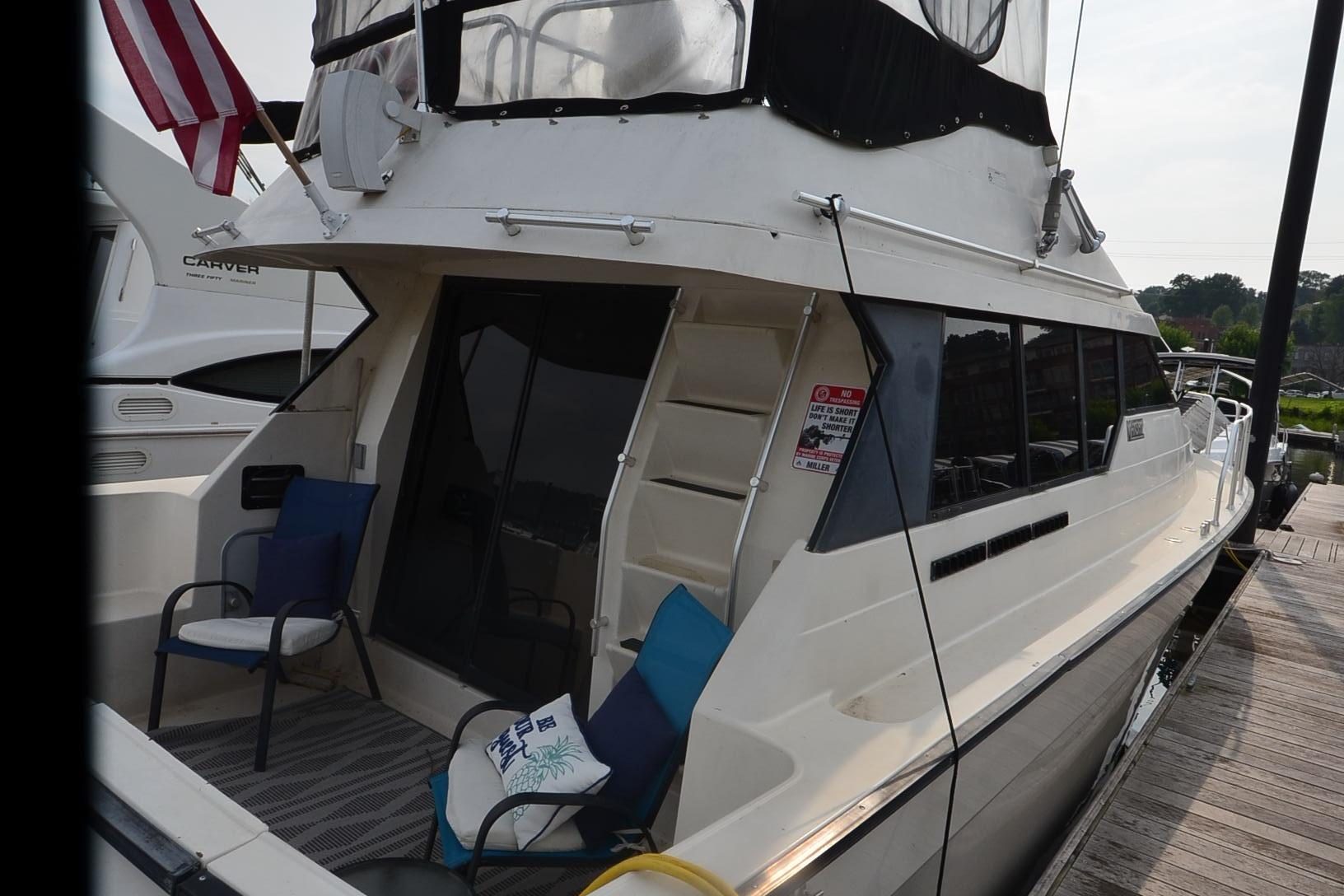 1988 Mainship Mediterranean Convertible yacht docked, featuring outdoor seating and American flag.