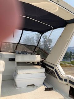 Interior of a boat with white seating and a black canopy.