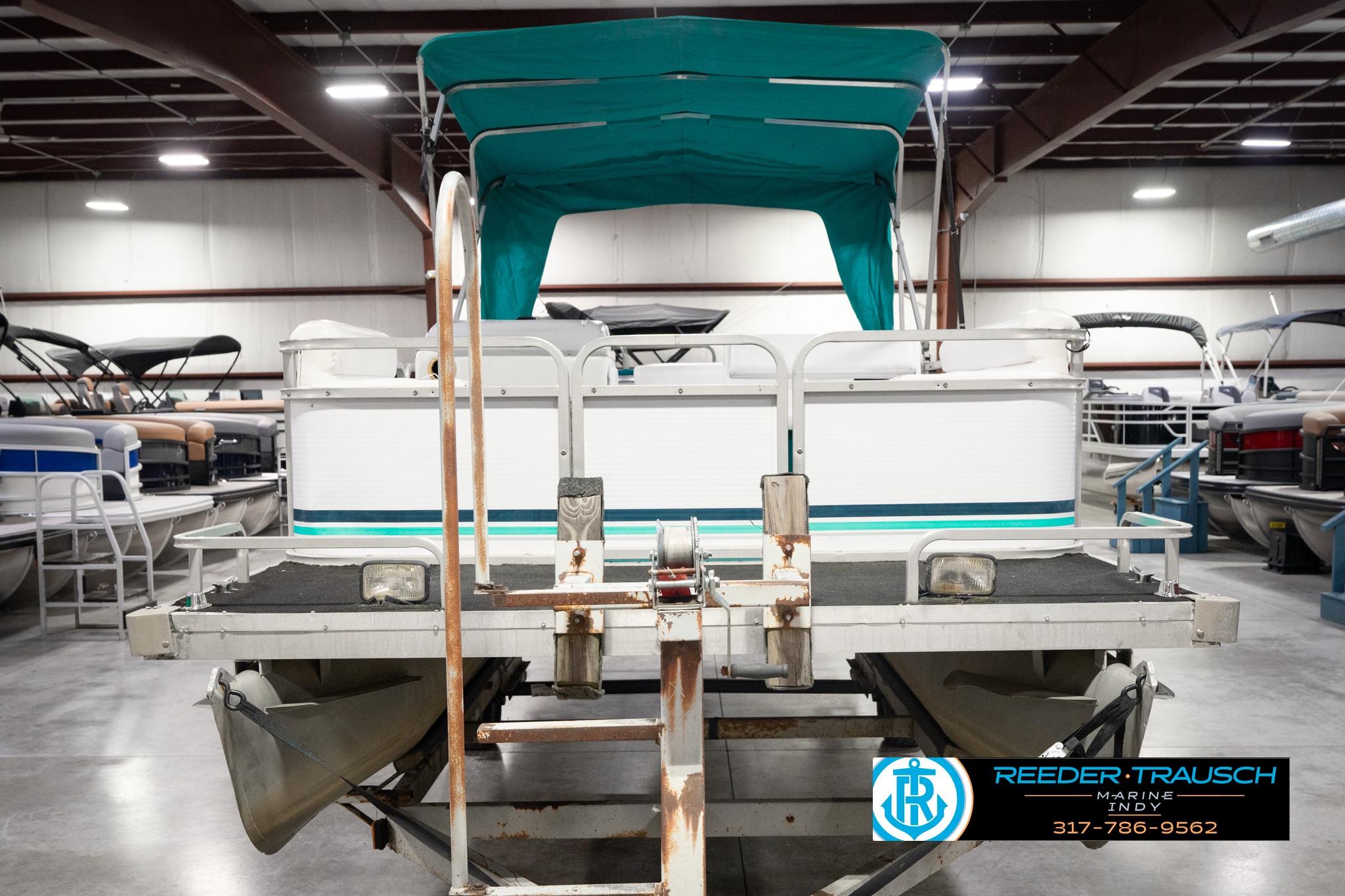 1992 Godfrey Sweetwater pontoon boat in indoor showroom with teal canopy.