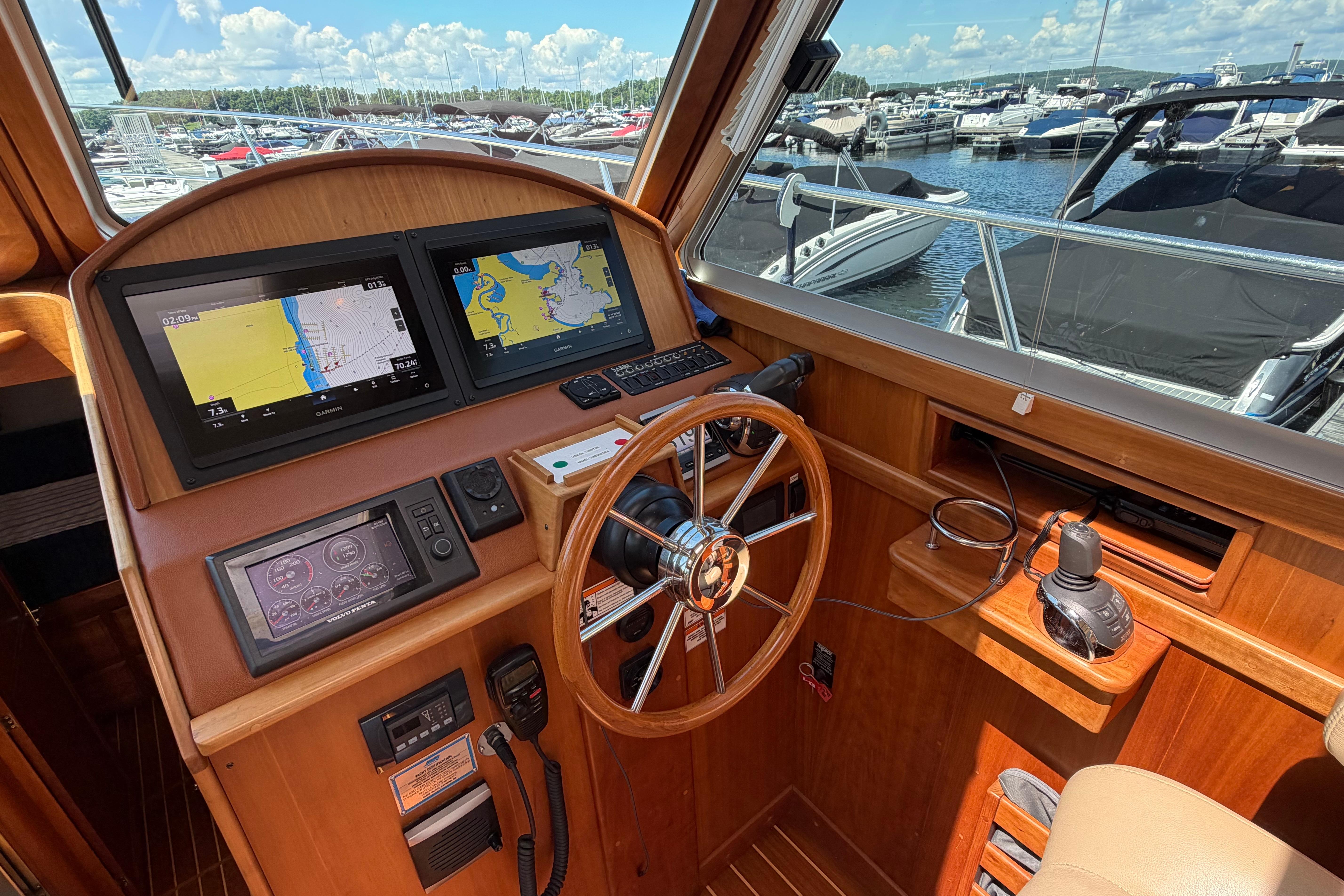 Helm of 2015 Sabre 38 Salon Express with navigation screens and wooden steering wheel.