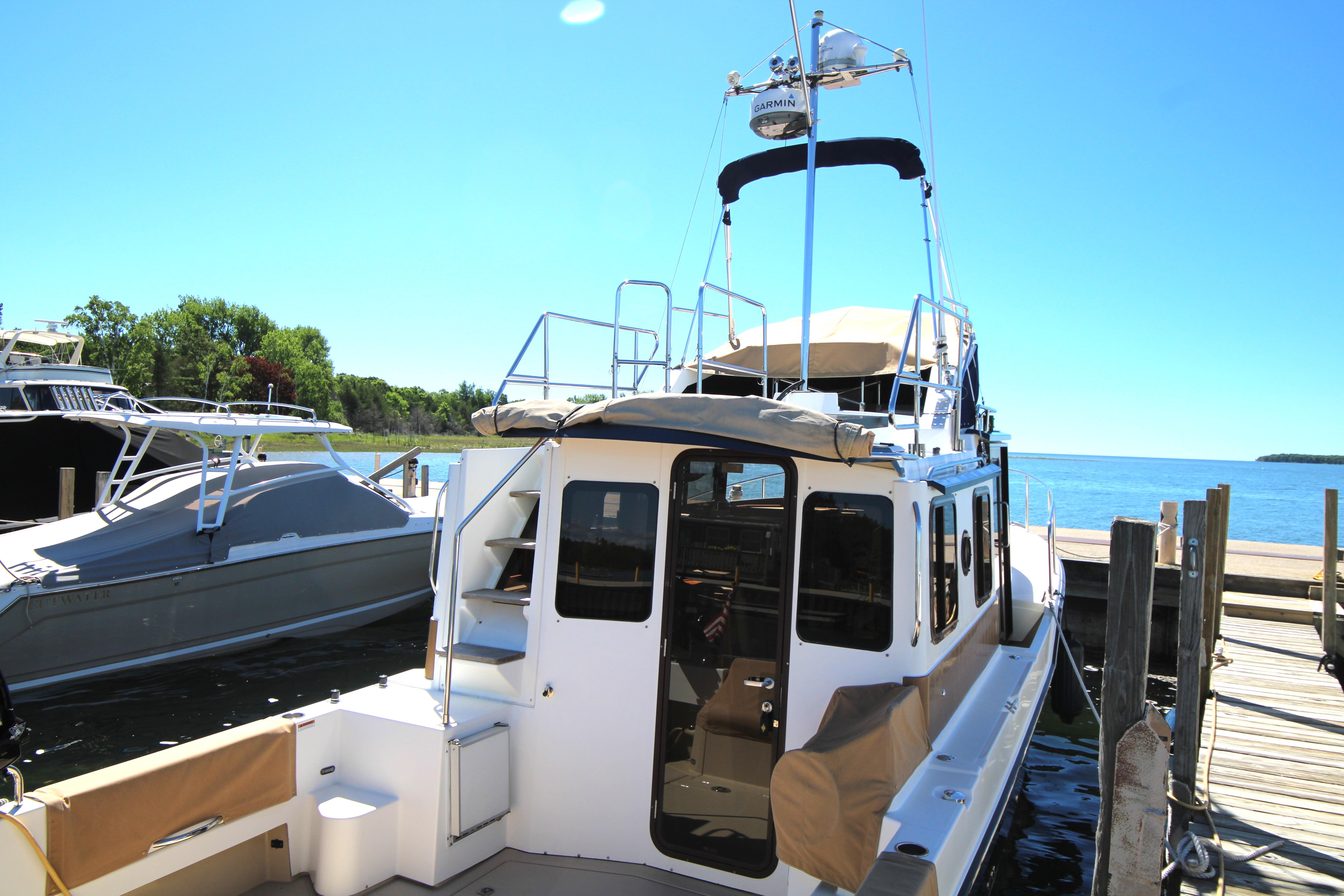 2013 Ranger Tugs R-31 CB docked by a serene waterfront.