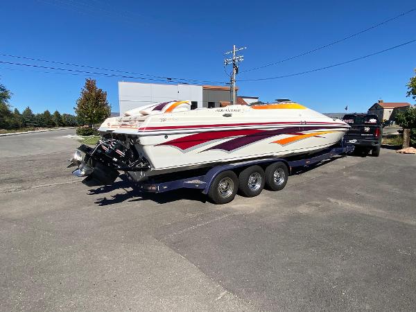 2002 Advantage Victory boat on trailer, vibrant graphics, parked outdoors under clear blue sky.