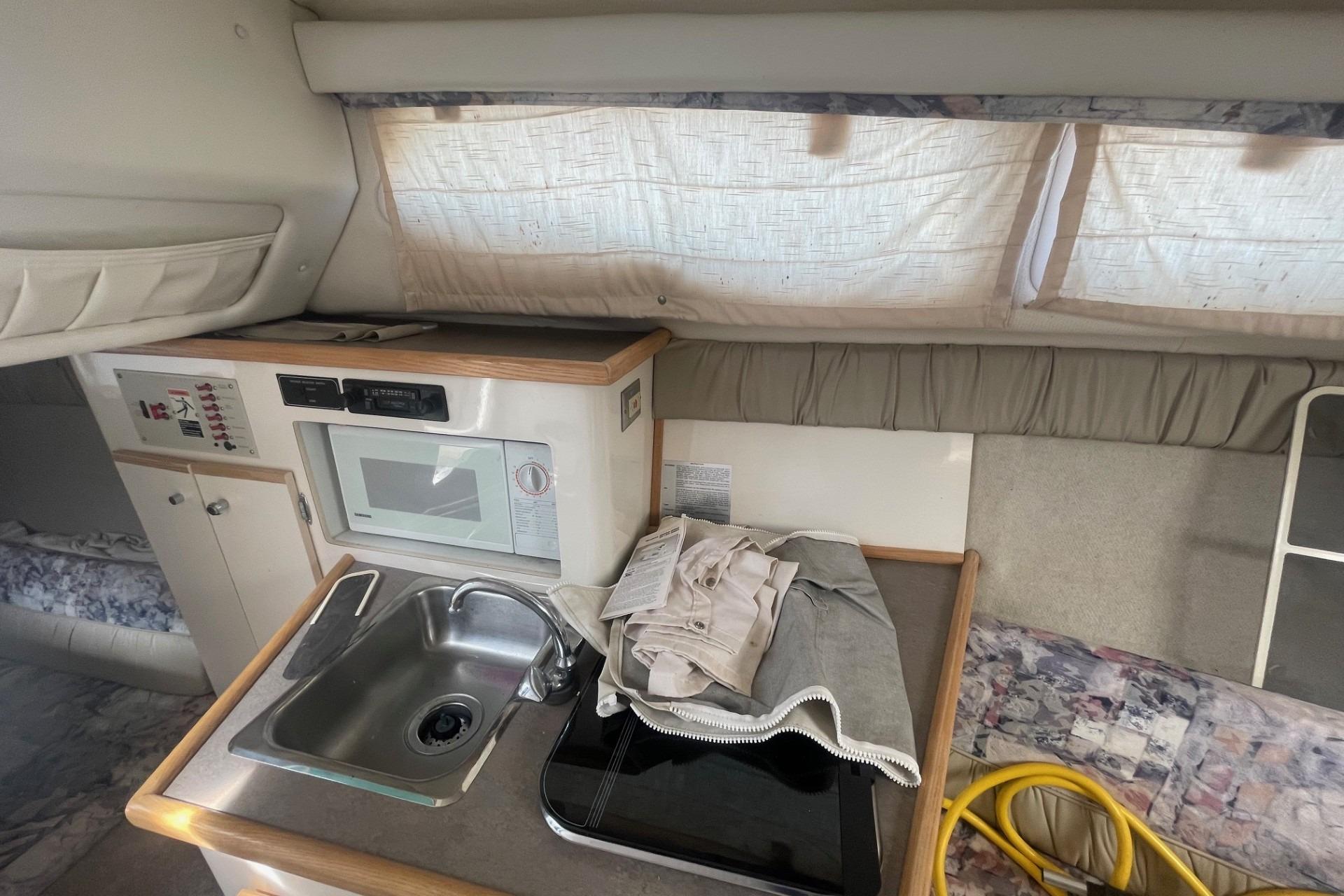 1997 Bayliner 2655 Ciera cabin interior with sink, microwave, and curtains.