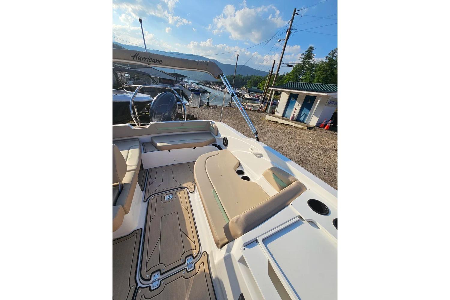 2025 Hurricane SunDeck Sport 205 OB boat interior with seating and helm, docked under sunny skies.