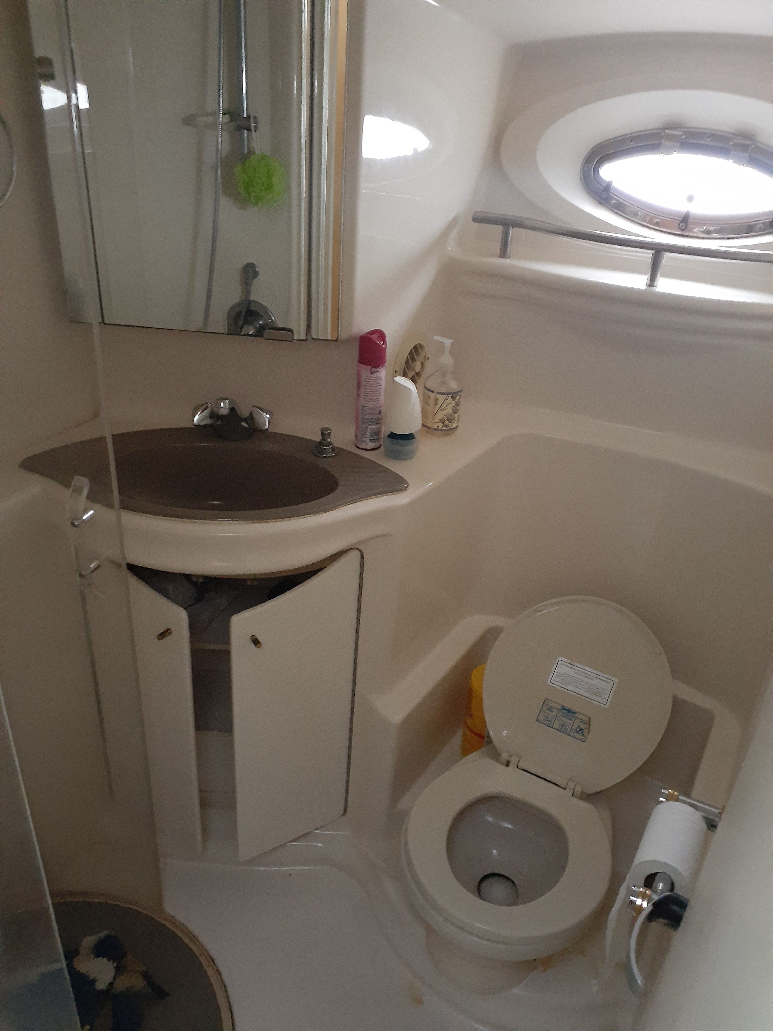 The image shows a boat bathroom with a sink, toilet, and shower.
