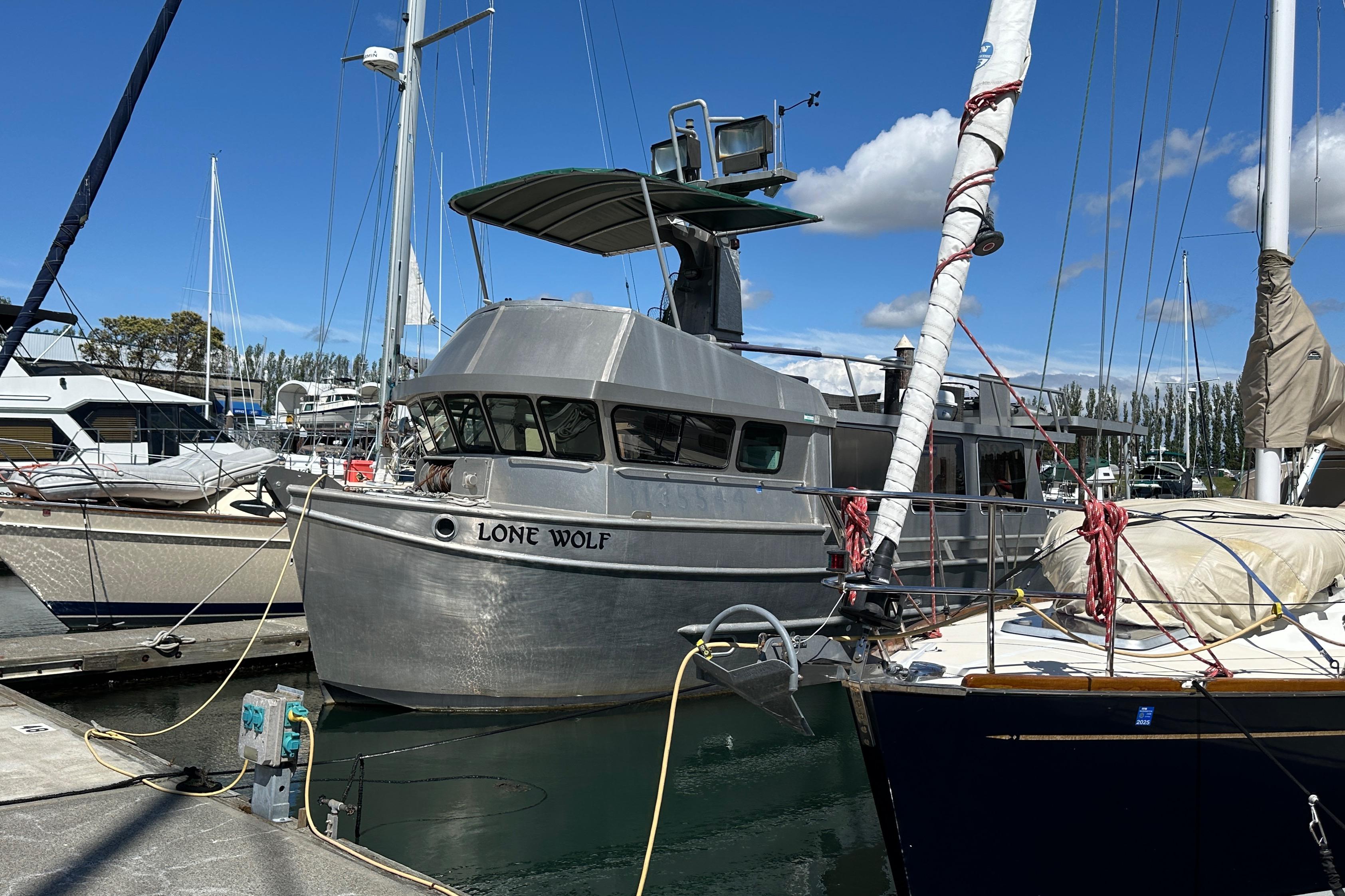 Custom 2002 Carlson Marine Trawler "Lone Wolf" docked at marina under blue sky.