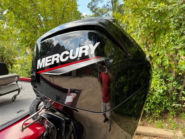 A Mercury outboard motor on a boat, surrounded by trees.