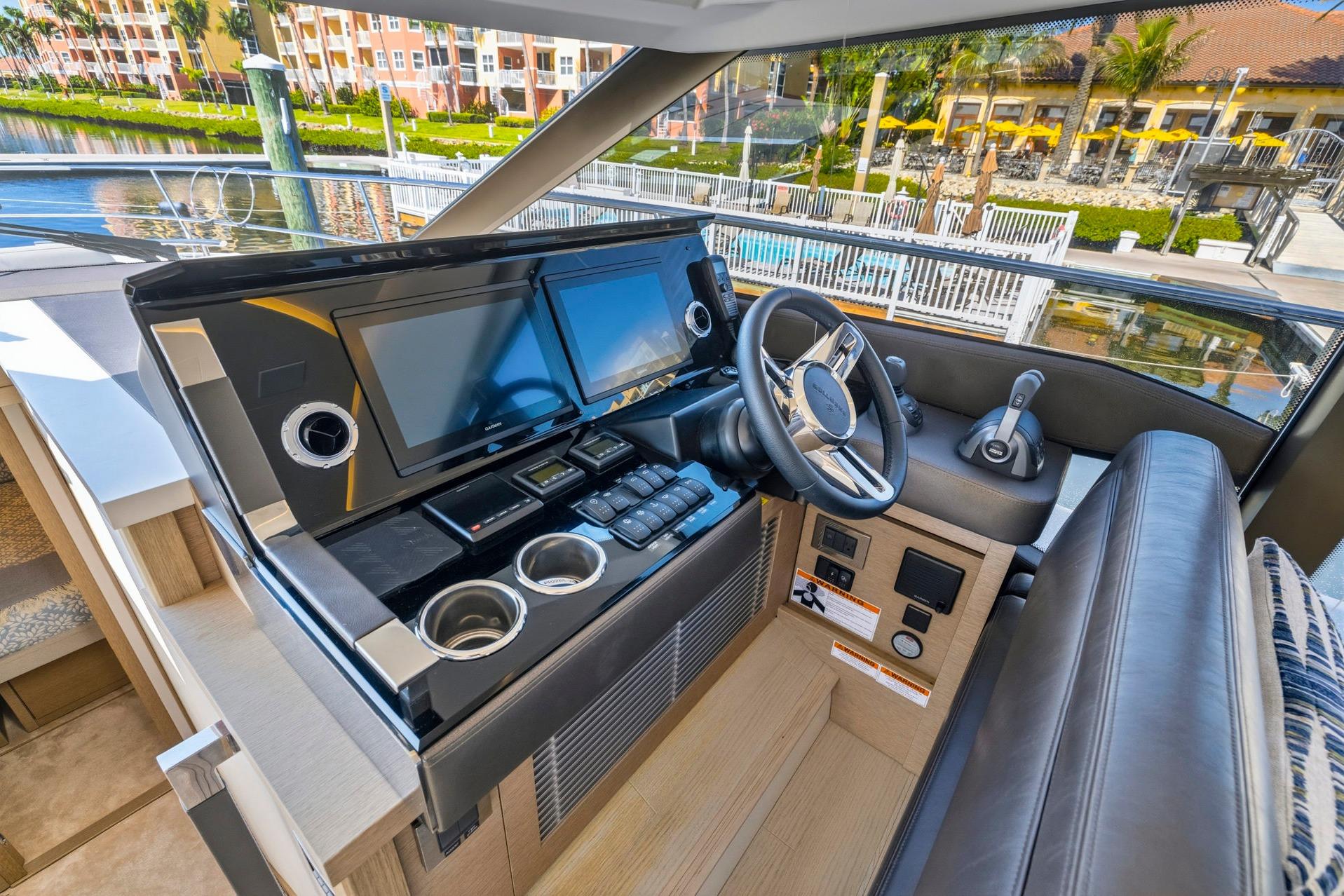 Modern helm station of 2022 Prestige 520 yacht with dual screens and luxurious seating.