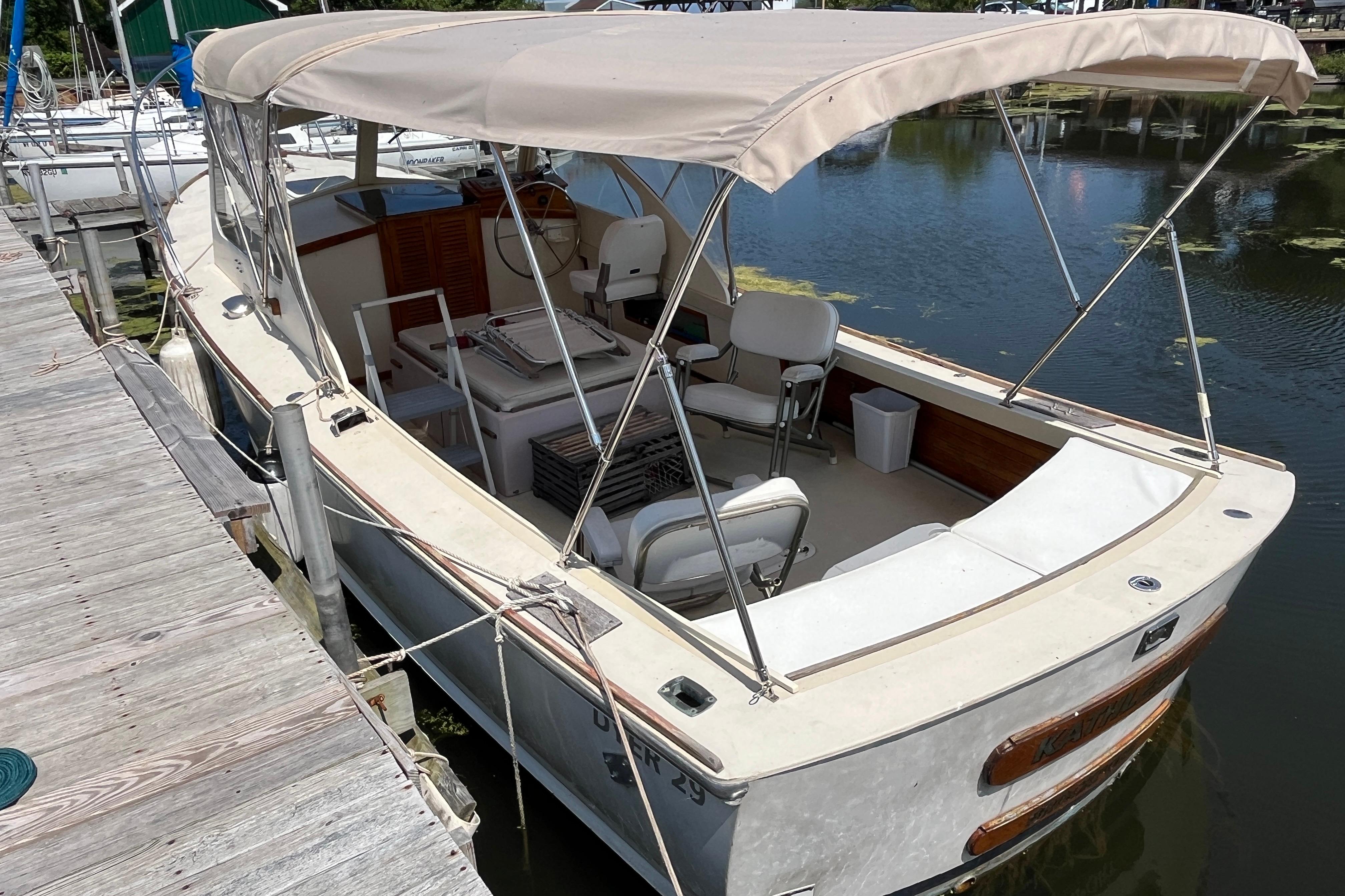 1981 Dyer 29 Flush Deck/Bass Boat docked, featuring canopy and seating.