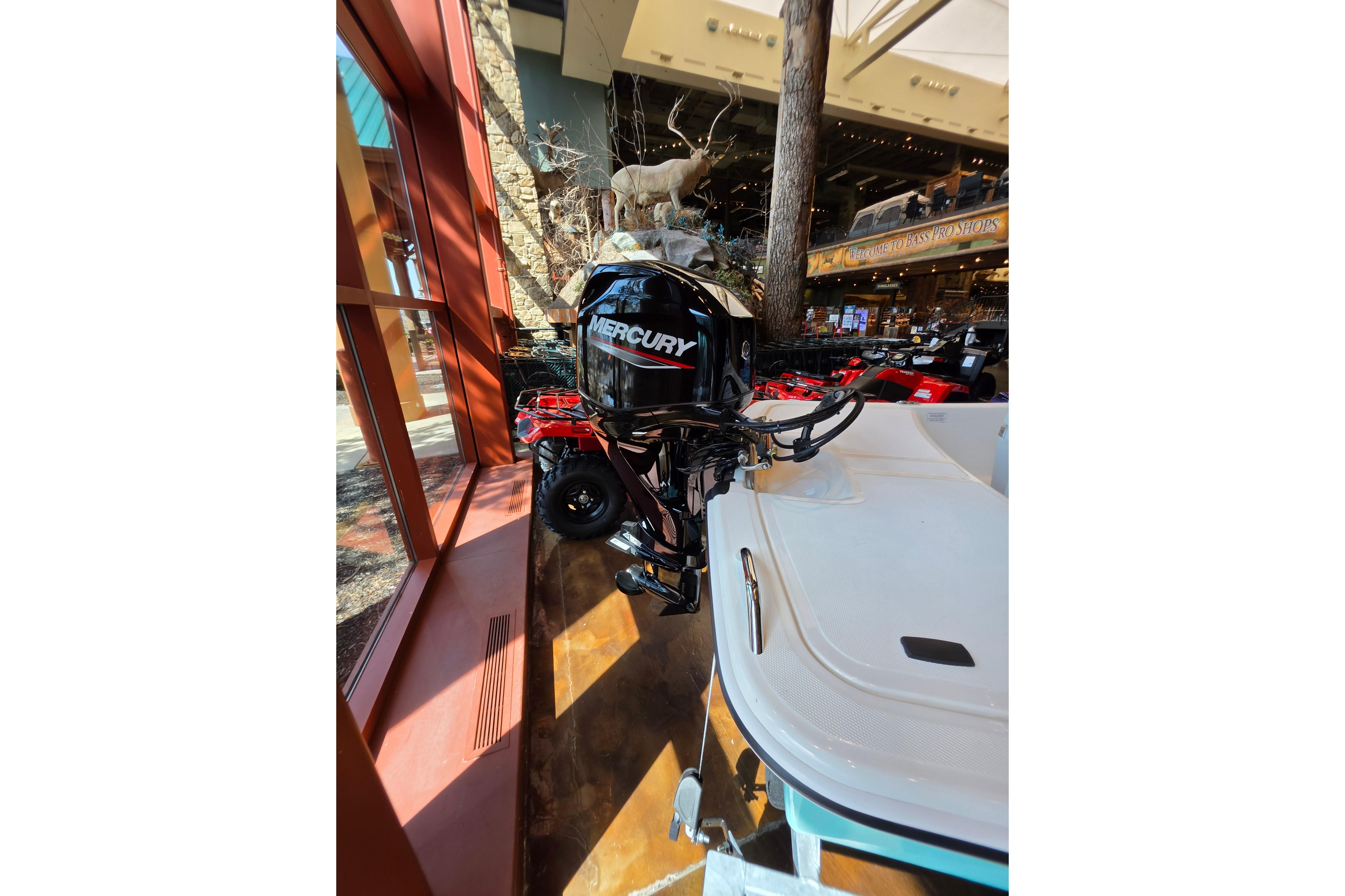 2026 Mako Pro Skiff 15 CC with Mercury outboard motor displayed indoors.