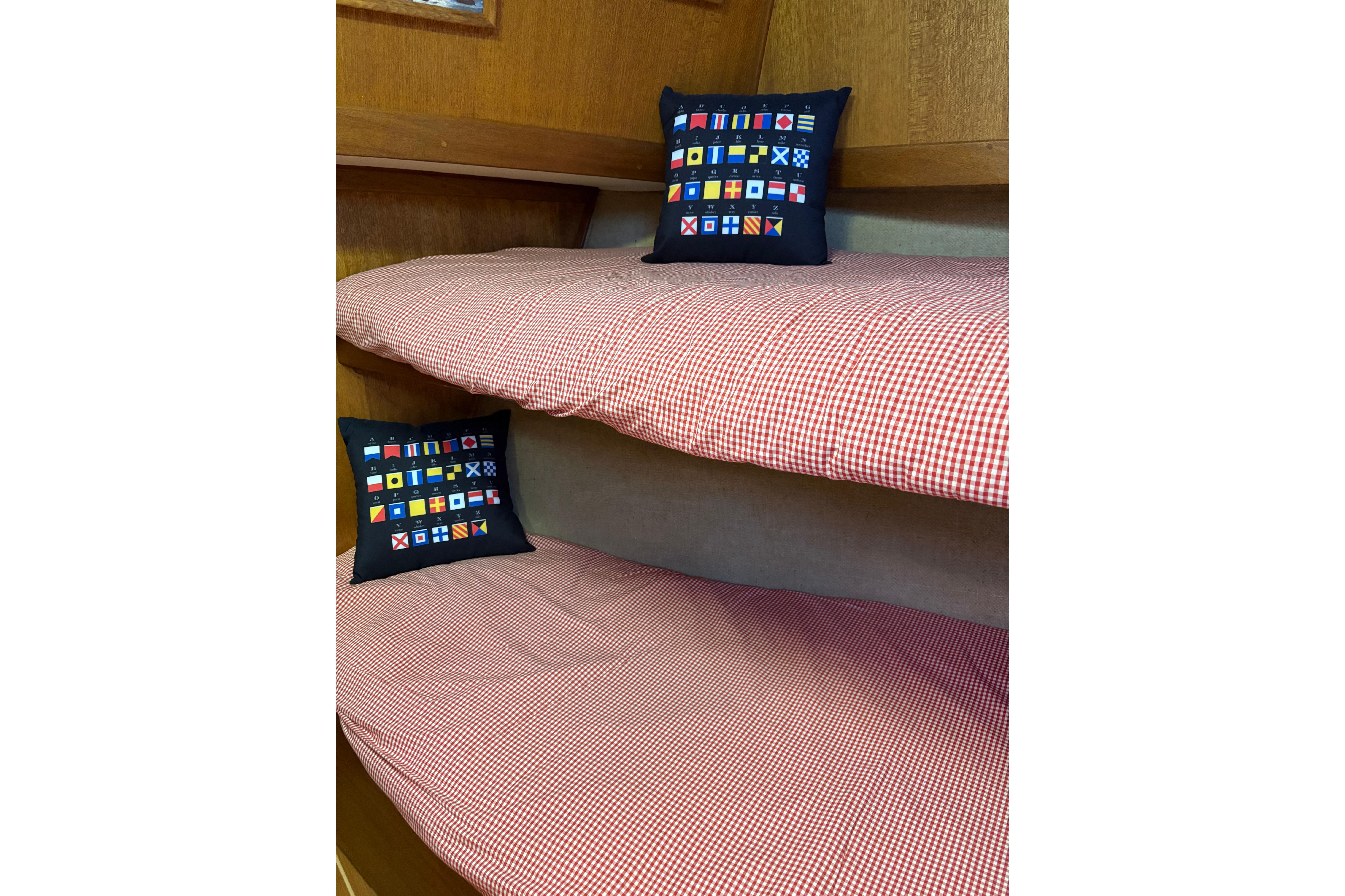 Bunk beds with checkered bedding and nautical pillows on a 1978 Californian 42 LRC boat.