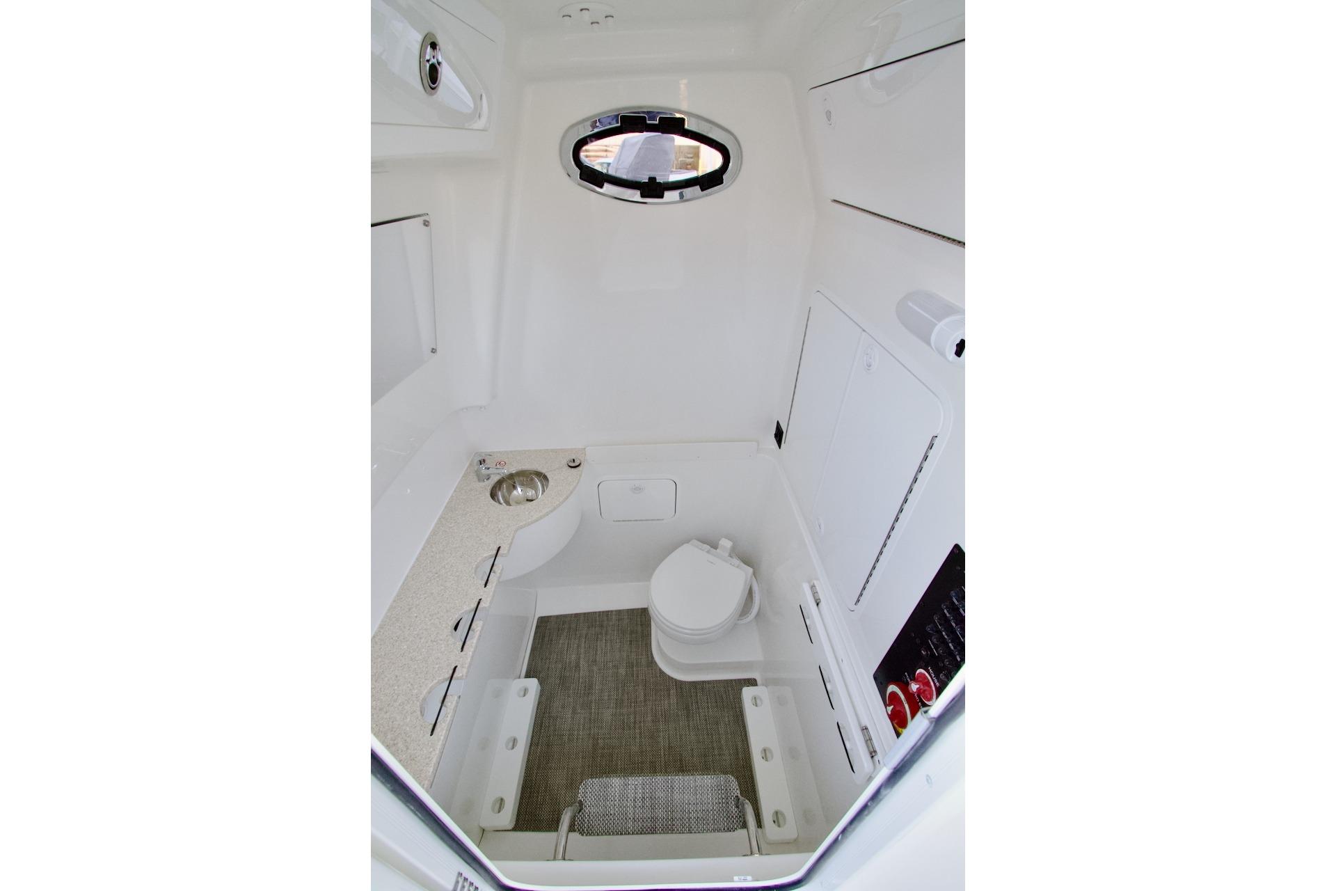 2026 Regulator 31 boat interior with compact bathroom, featuring a toilet, sink, and window.