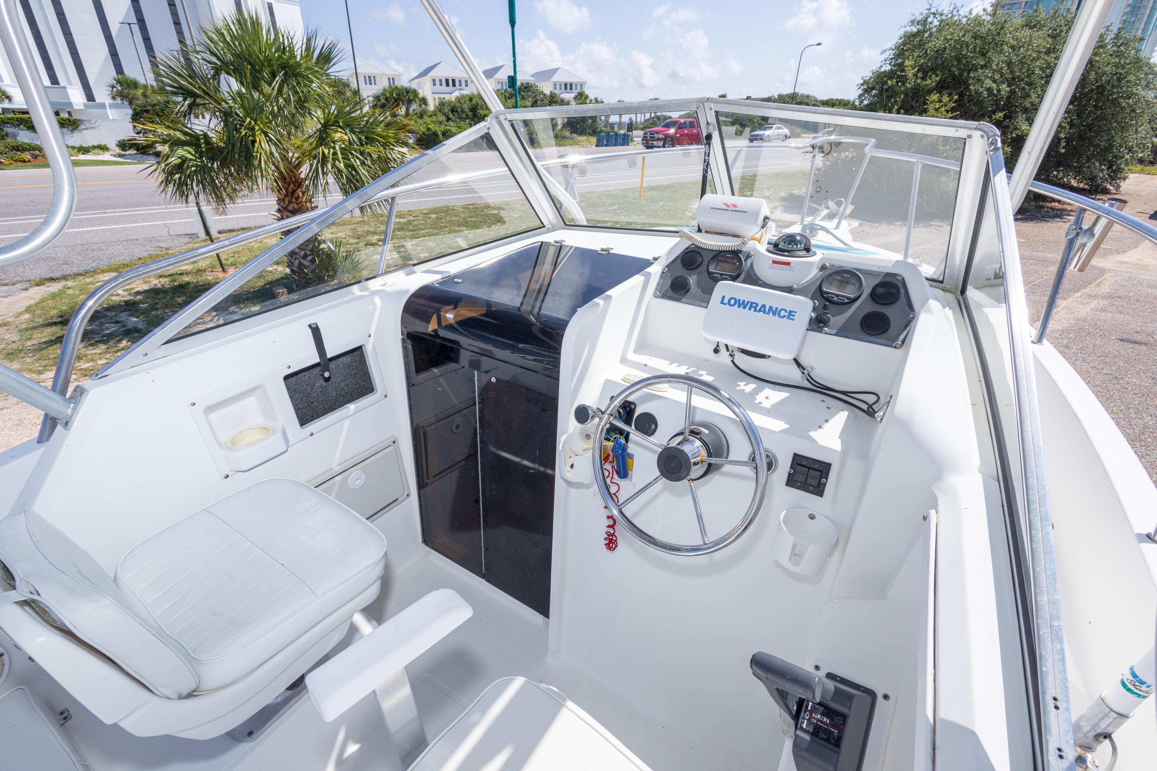 1999 Aquasport 225 Explorer boat cockpit with steering wheel and navigation equipment.
