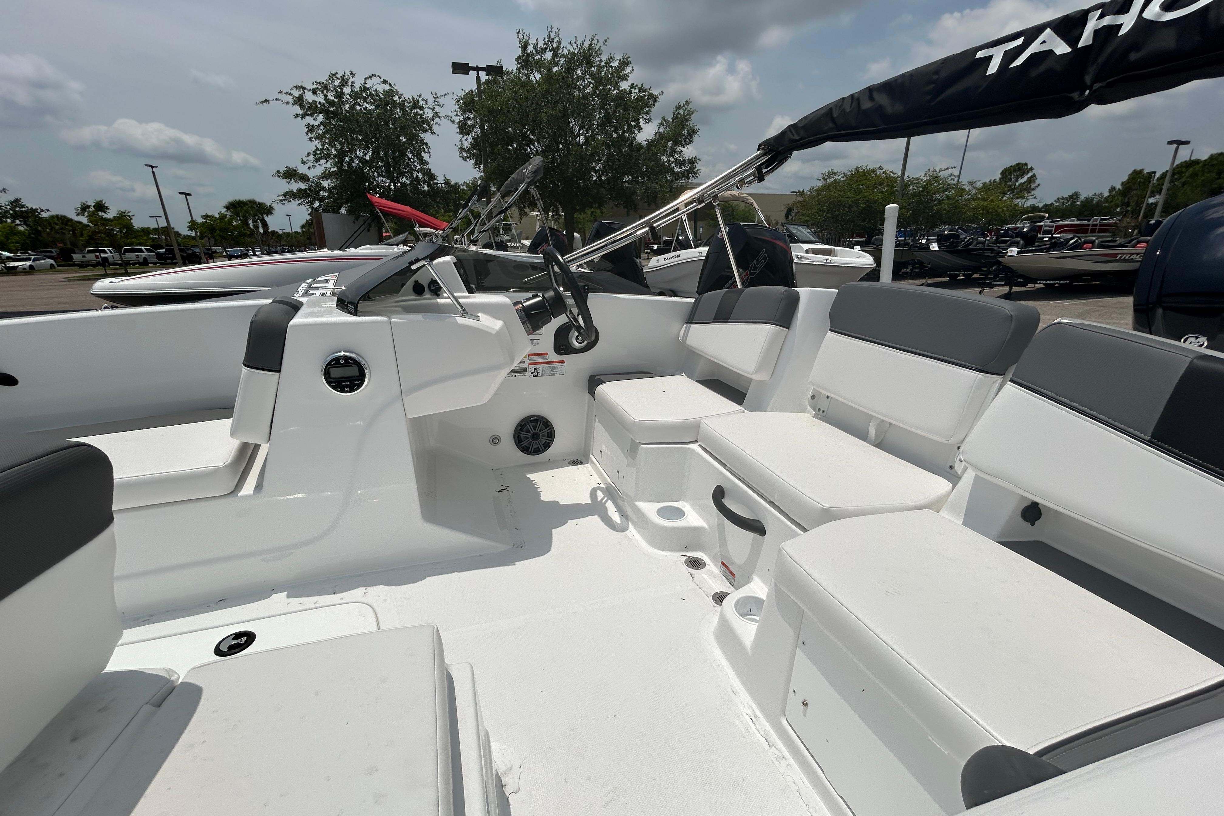 2026 Tahoe T18 boat interior with white seating and steering wheel, parked outdoors.